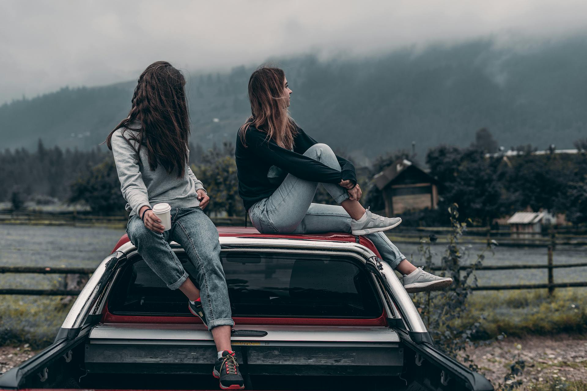 Two women sitting on a vehicle roof | Source: Pexels