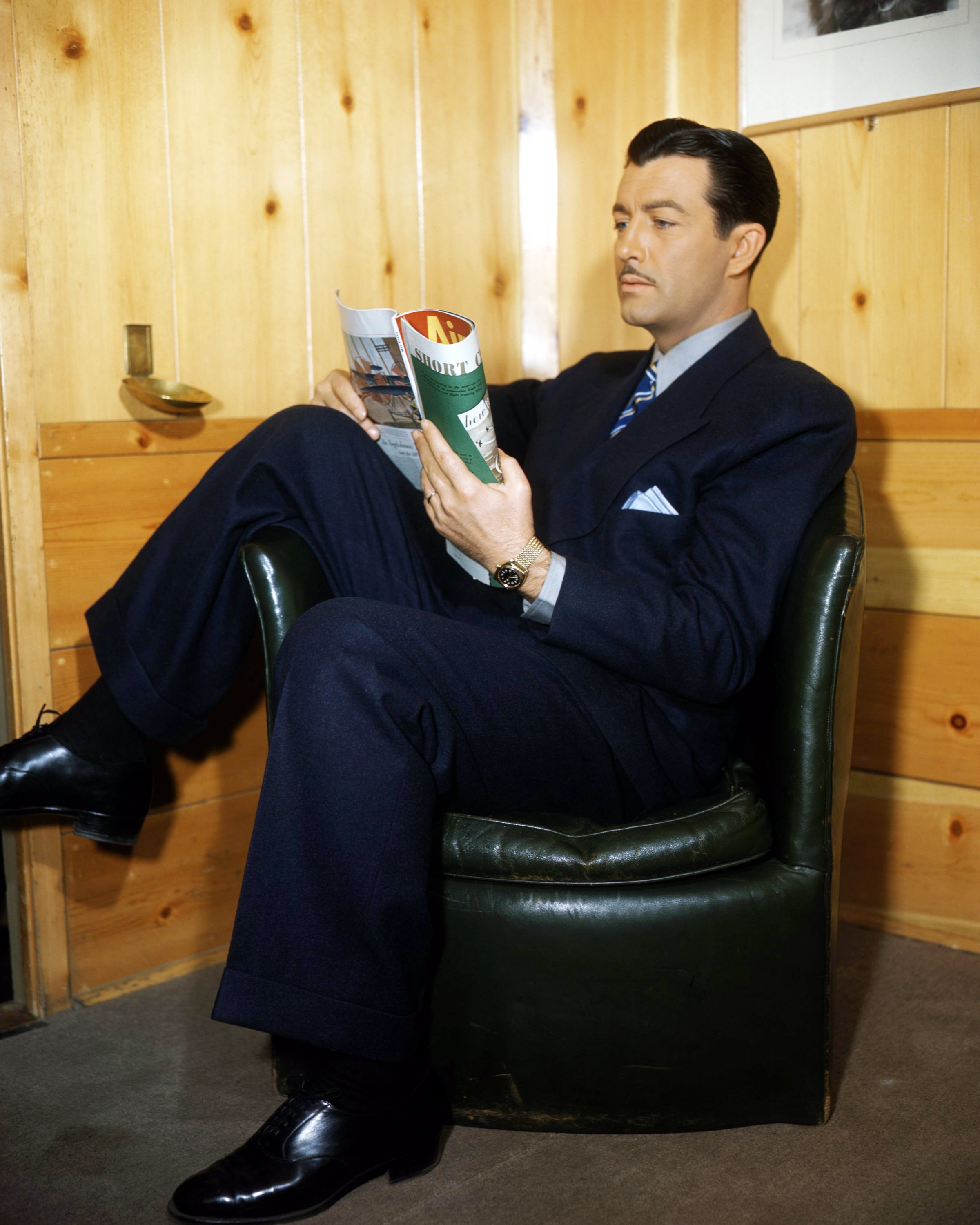 American actor Robert Taylor (1911 - 1969) sitting in an armchair and reading a magazine, circa 1940. | Source: Getty Images
