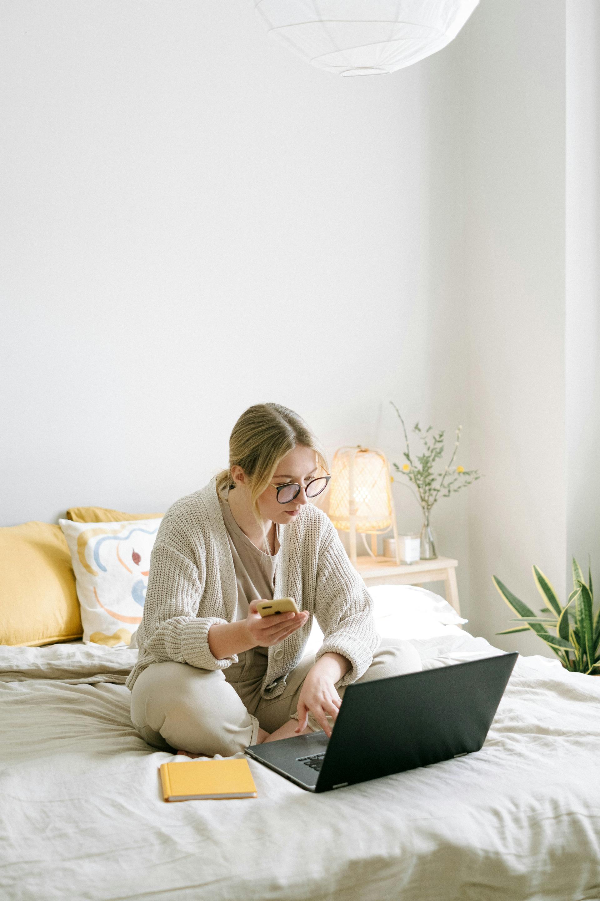 A woman using a laptop and holding a phone | Source: Pexels