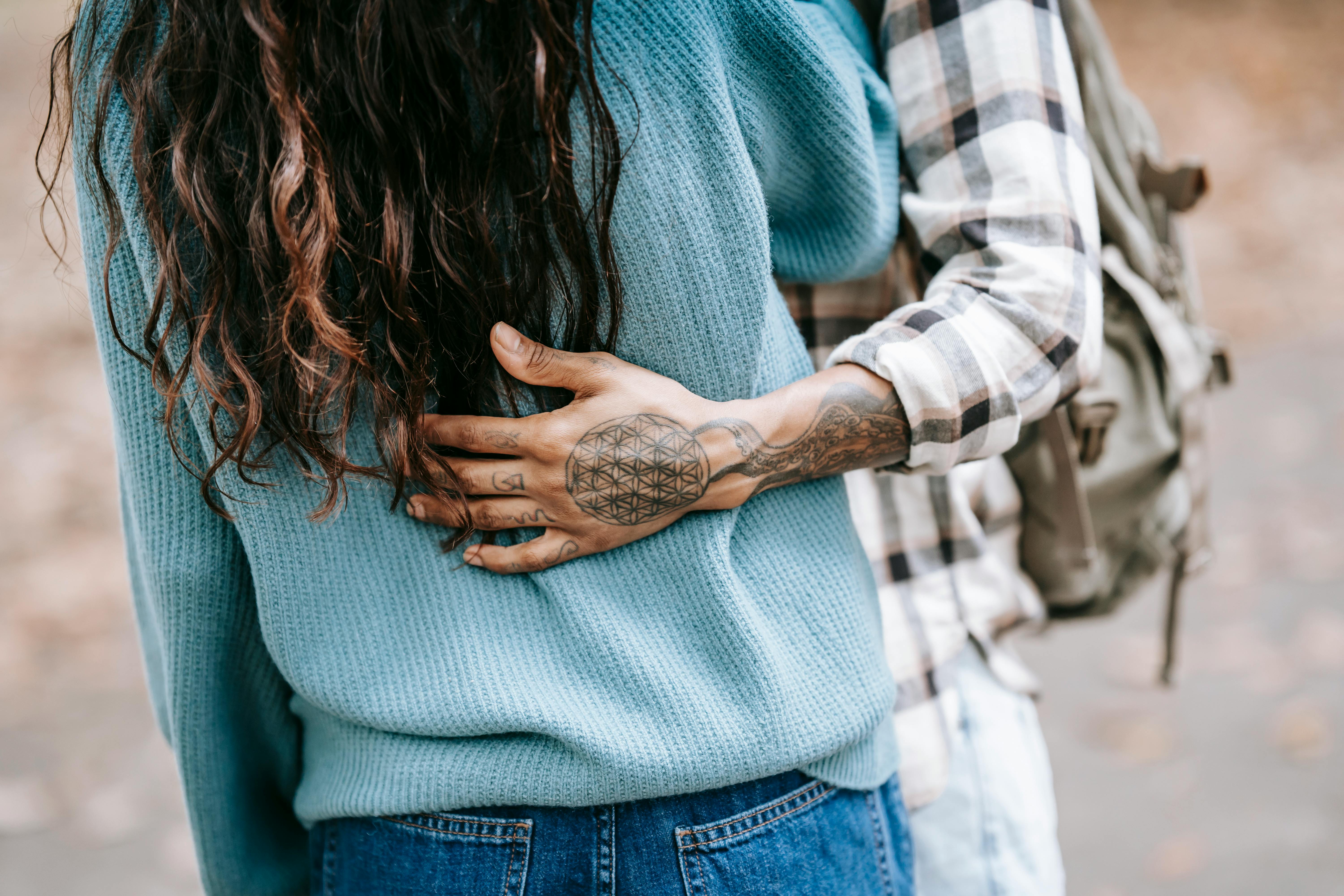A man with tattoos gently cuddling girlfriend | Source: Pexels