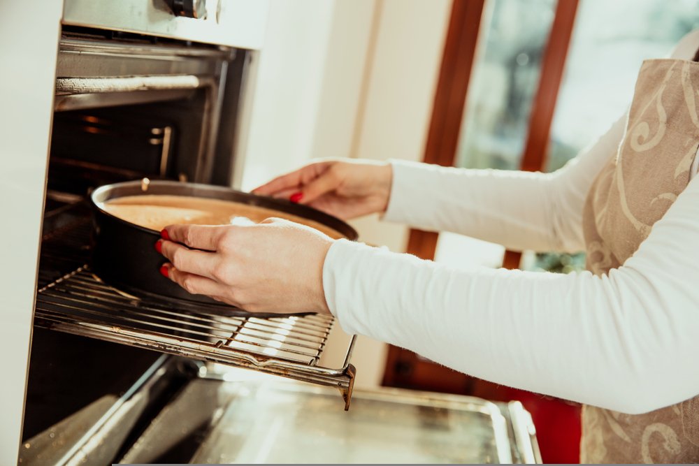 Mujer metiendo torta al horno. | Foto: Shutterstock.