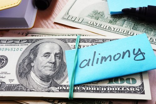 $100 bills tied together with a note designating it as alimony. | Source: Shutterstock.
