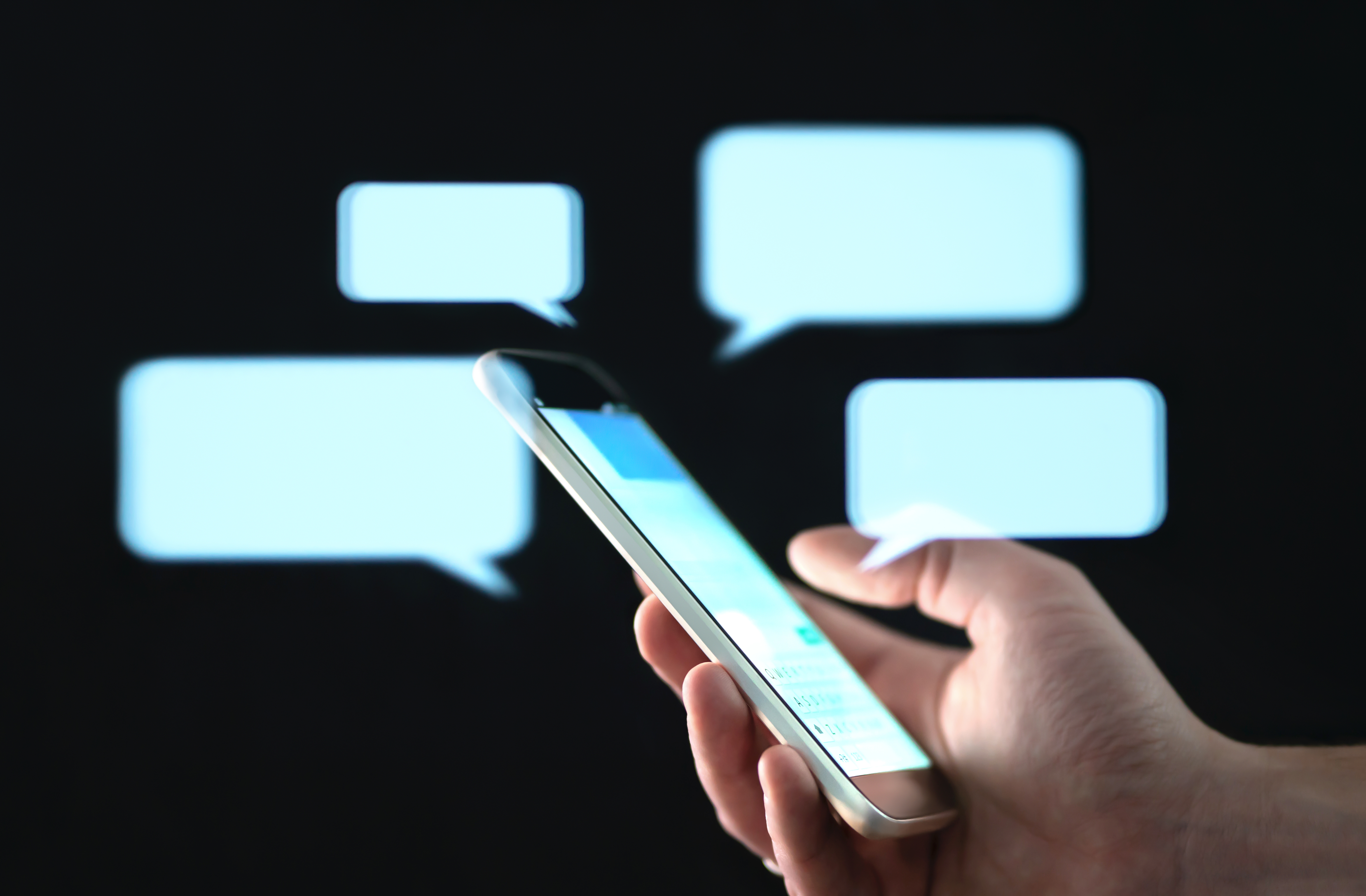 A hand holding a phone surrounded by speech bubbles | Source: Shutterstock