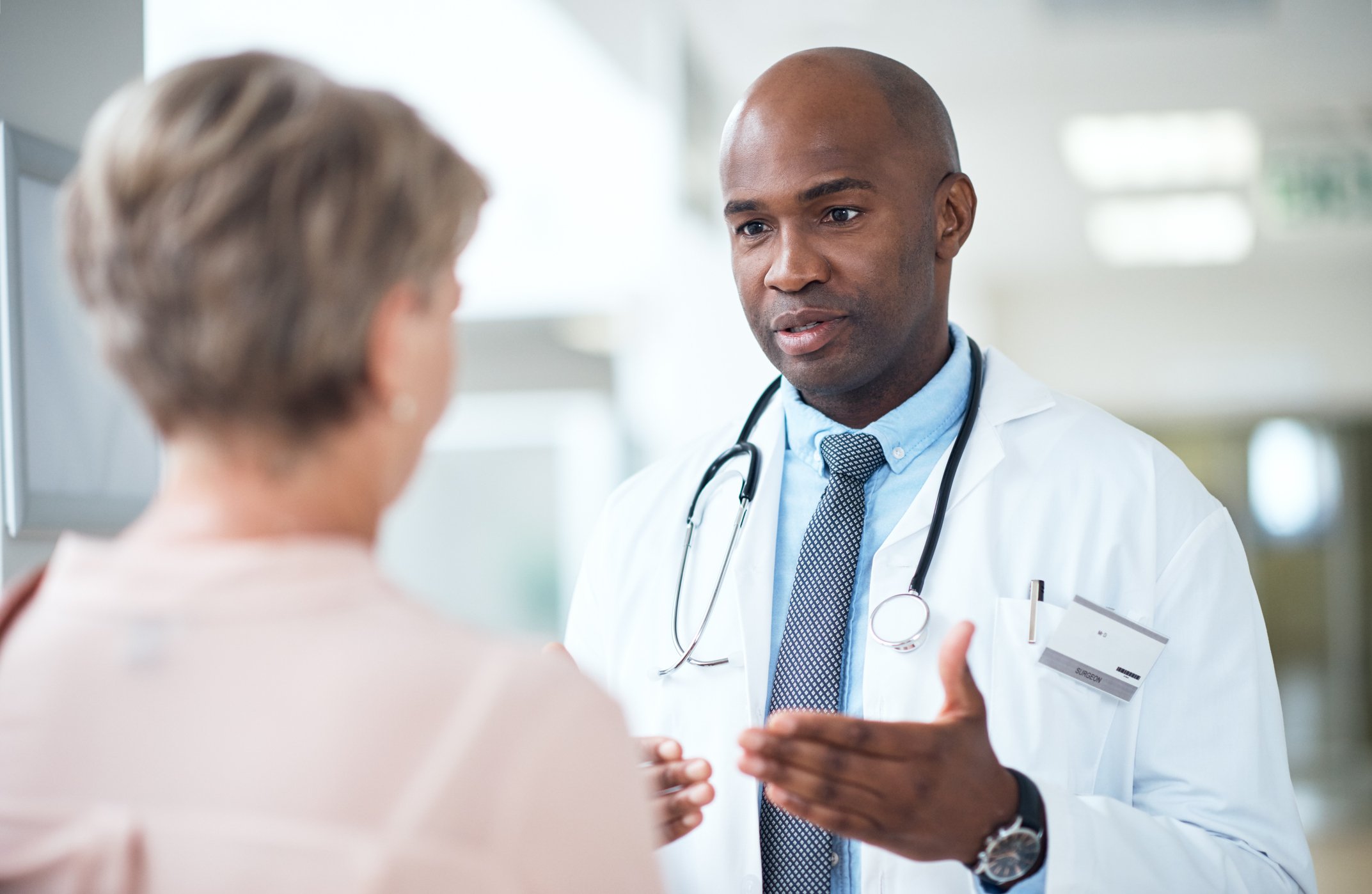 A mature male doctor talking to a lady in the hospital corridor | Photo: Getty Images