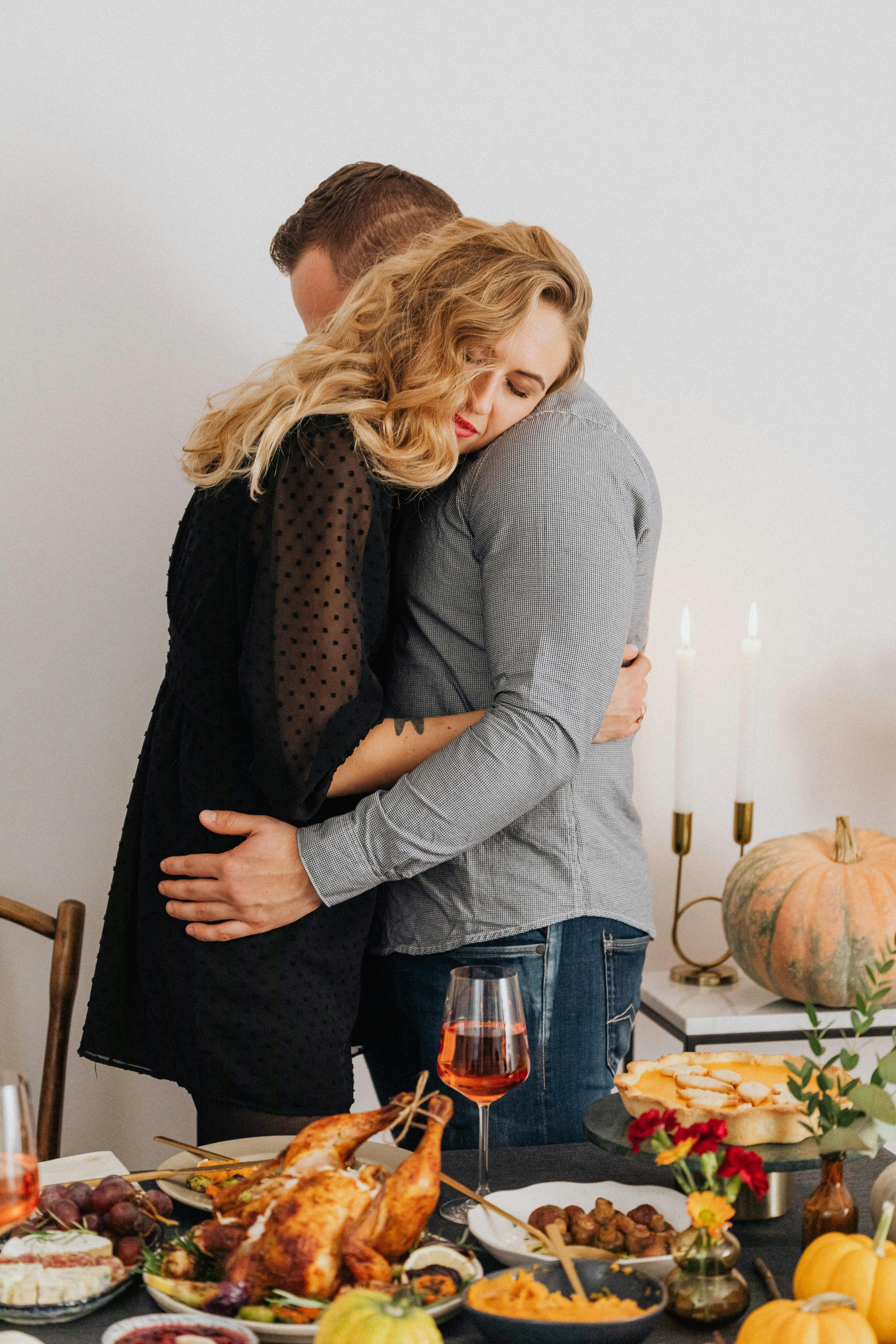 A couple hugging near a table set with food | Source: Pexels