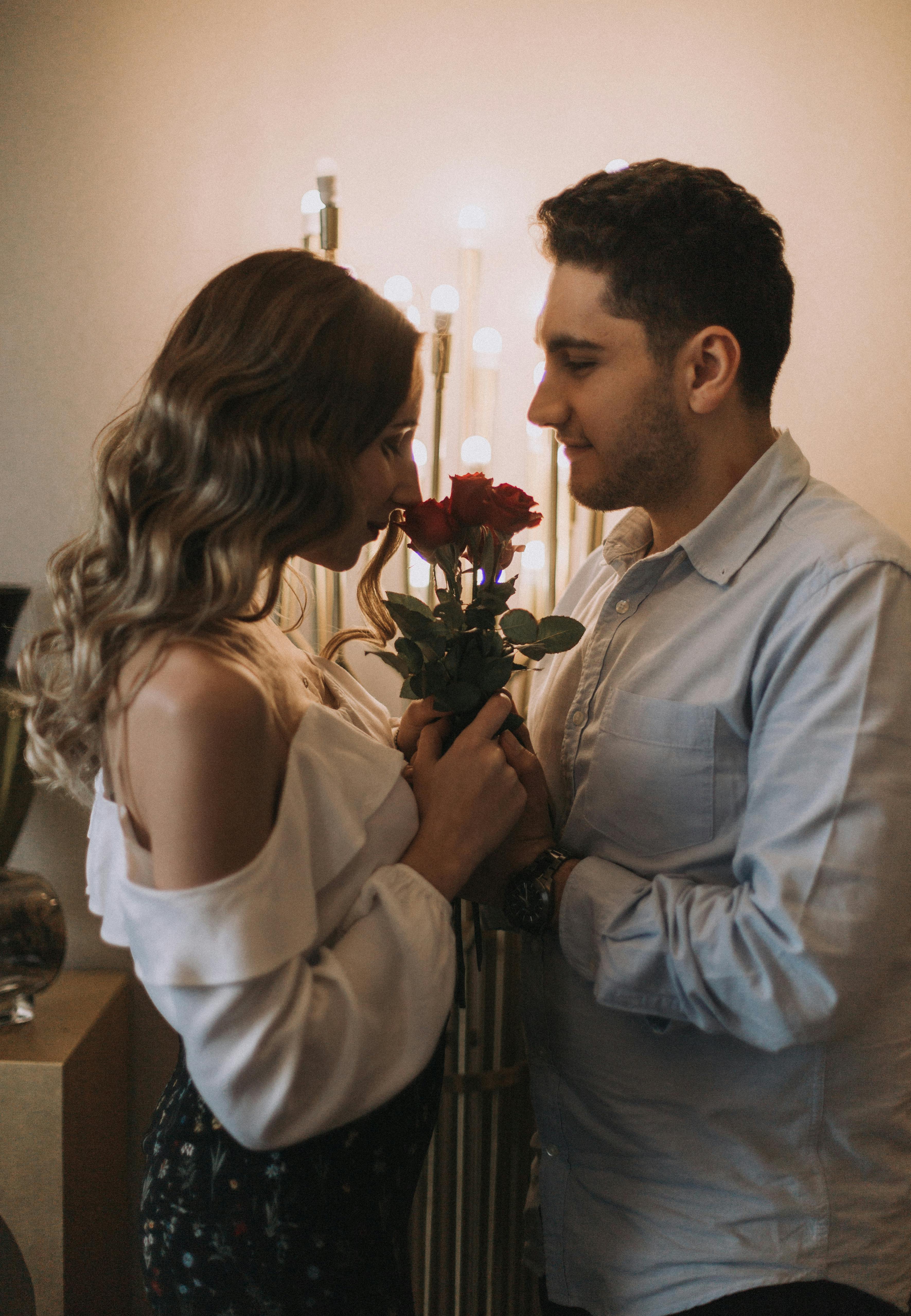 A couple staring at each other with a bunch of roses between them  | Source: Pexels