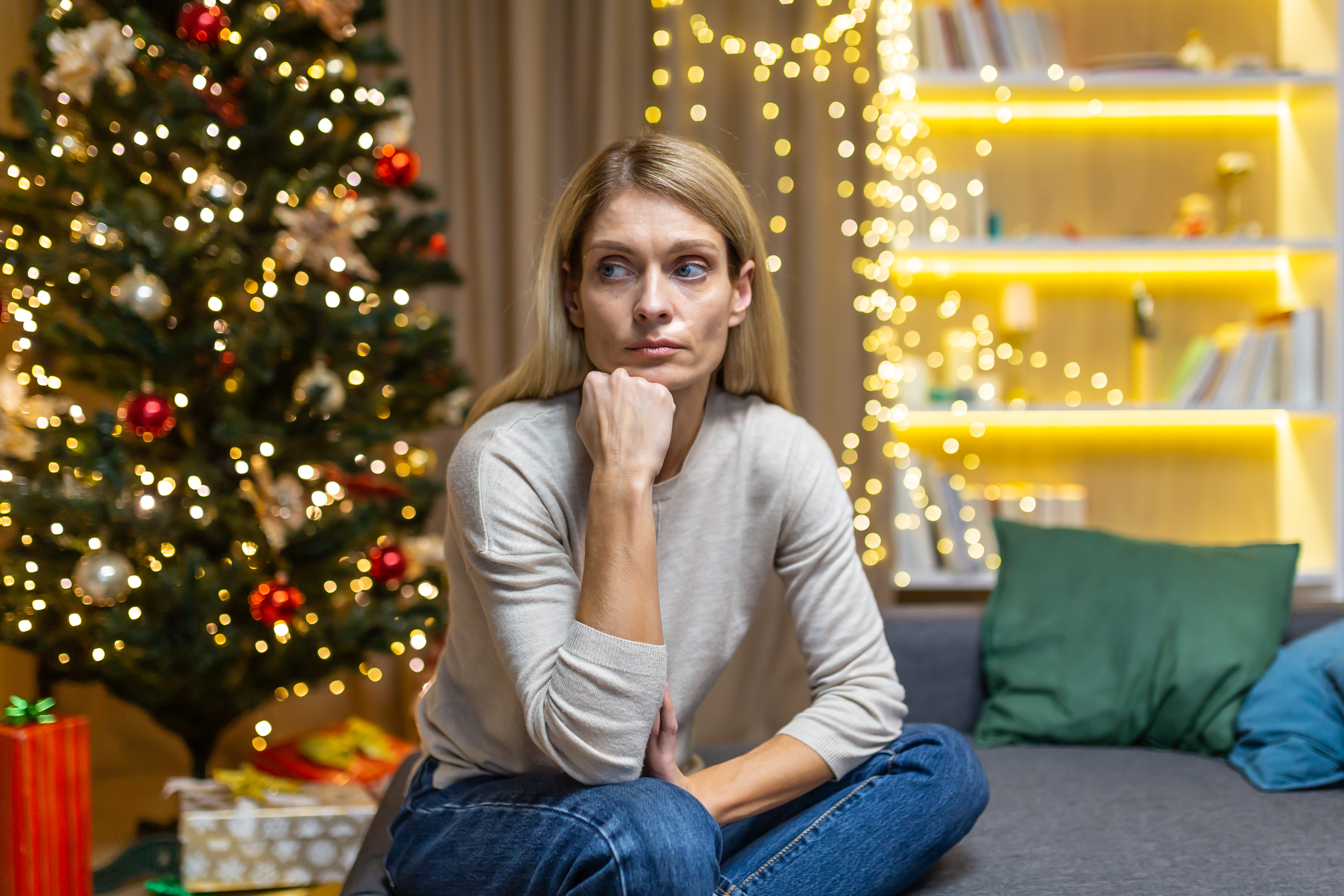 A sad woman sitting in front of a Christmas tree | Source: Getty Images