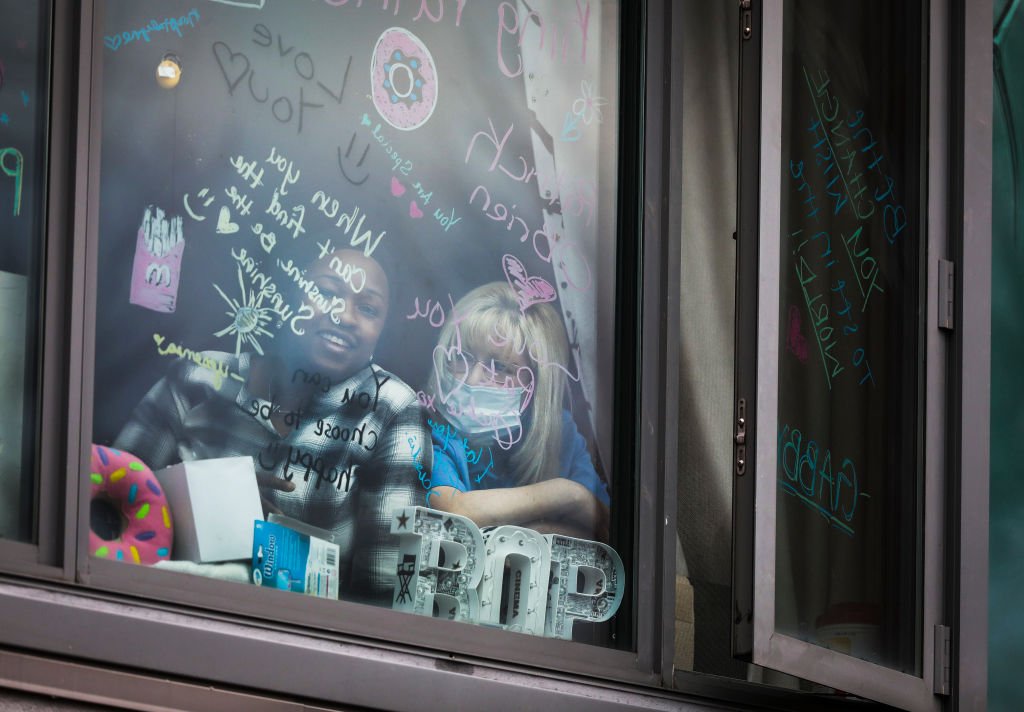 Residentes del Centro Leonard Florence para Vivir observan desde su ventana, el 20 de marzo de 2020, en medio de las regulaciones gubernamentales debido a la propagación del coronavirus. | Foto de Erin Clark/ a través de Getty Images