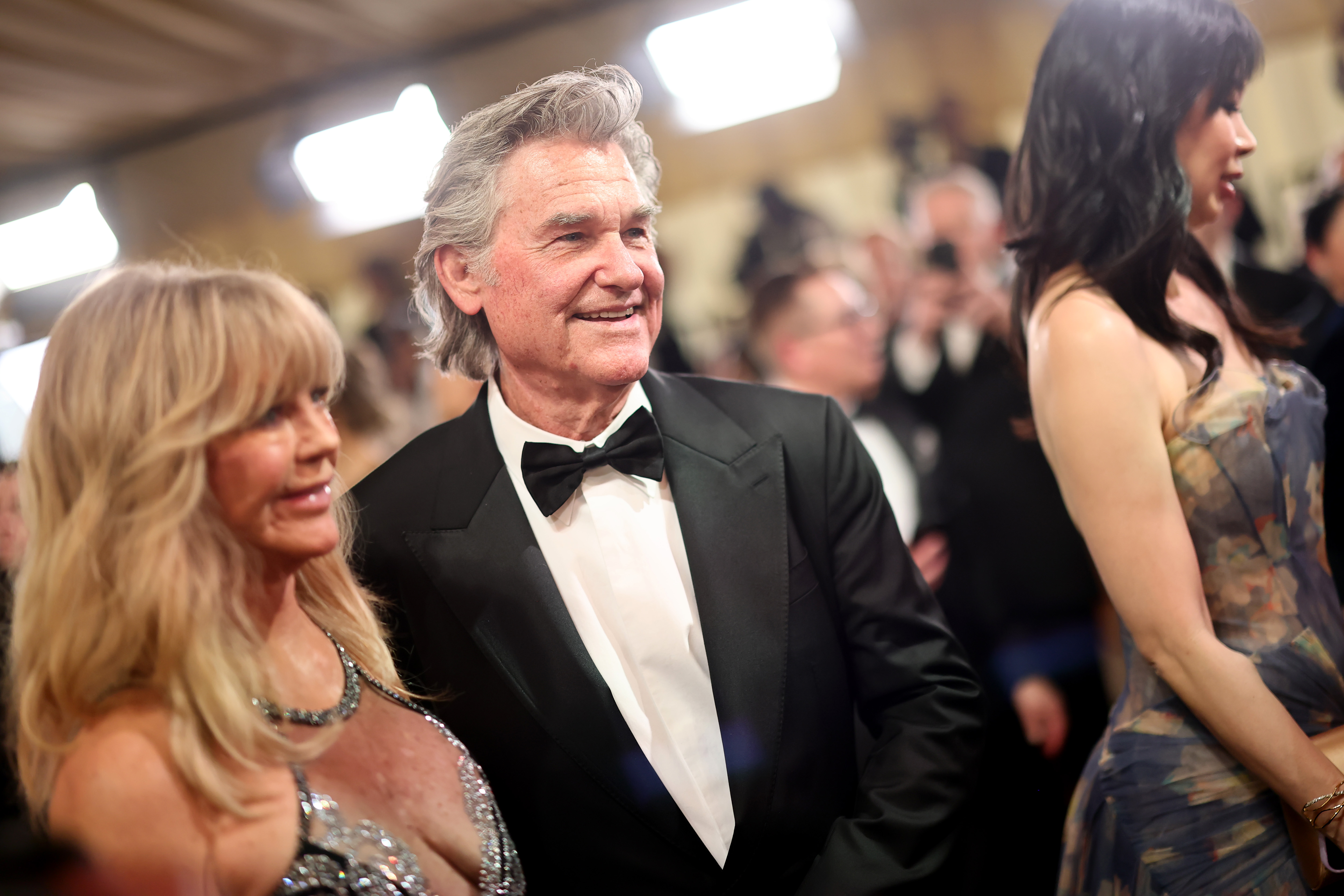 Goldie Hawn and Kurt Russell share a red carpet moment at the Oscars, with Russell in a classic black tuxedo as the longtime couple moves through the crowd of photographers and guests.