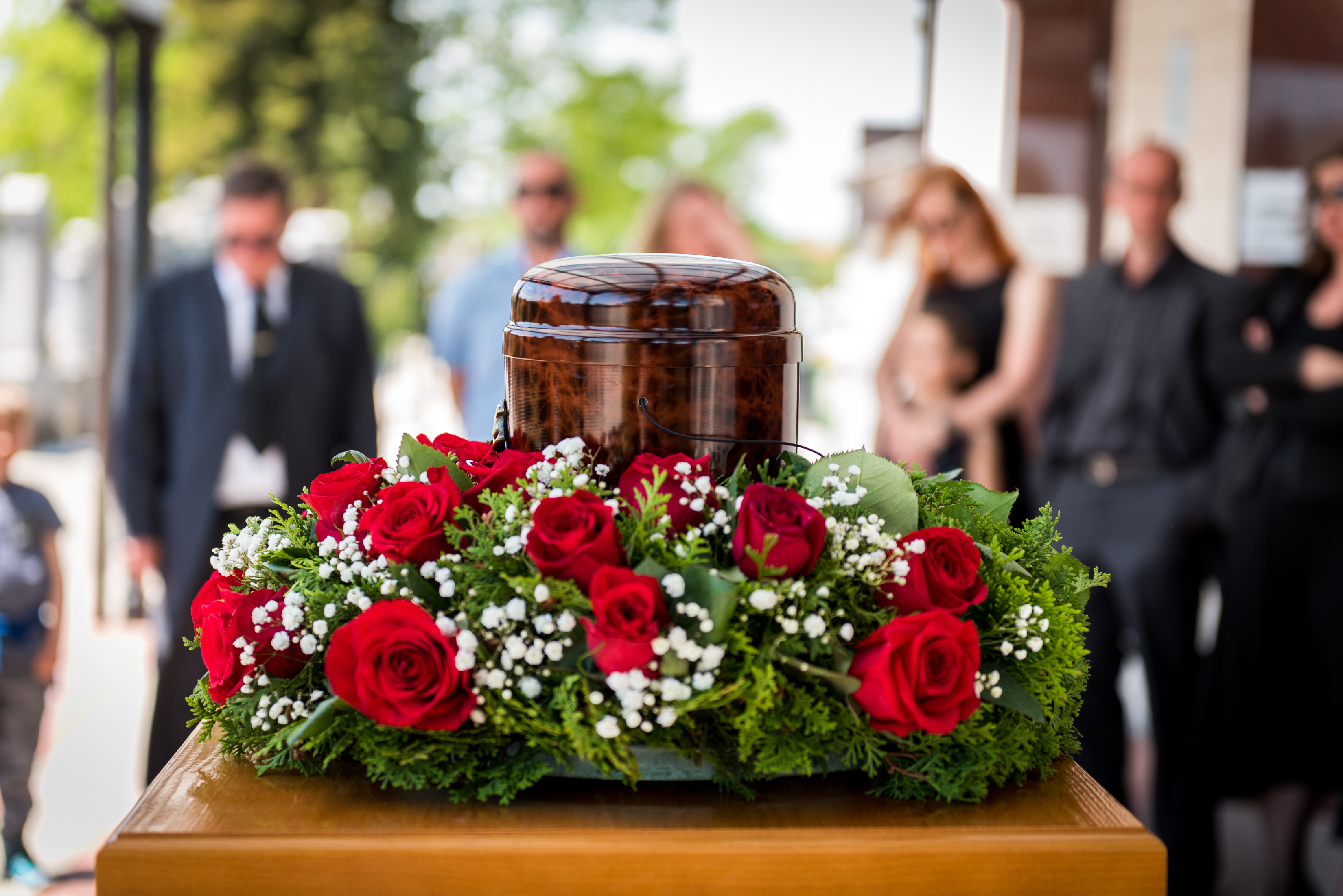 Funerary urn with ashes of dead and flowers at funeral. | Source: Shutterstock
