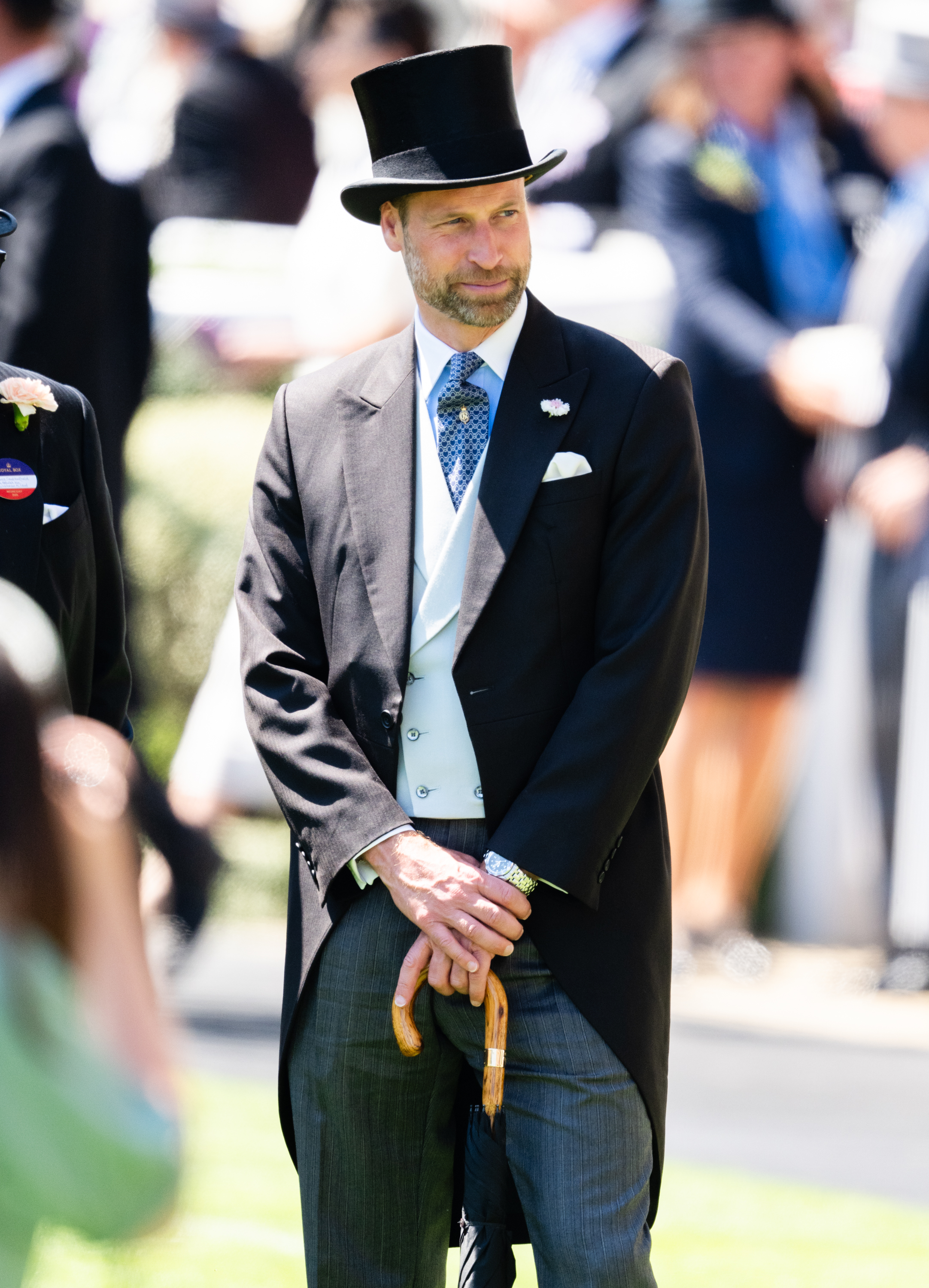 Prince William stands poised on the grounds of Ascot Racecourse, dressed in traditional morning attire and holding a signature umbrella during day two of Royal Ascot.