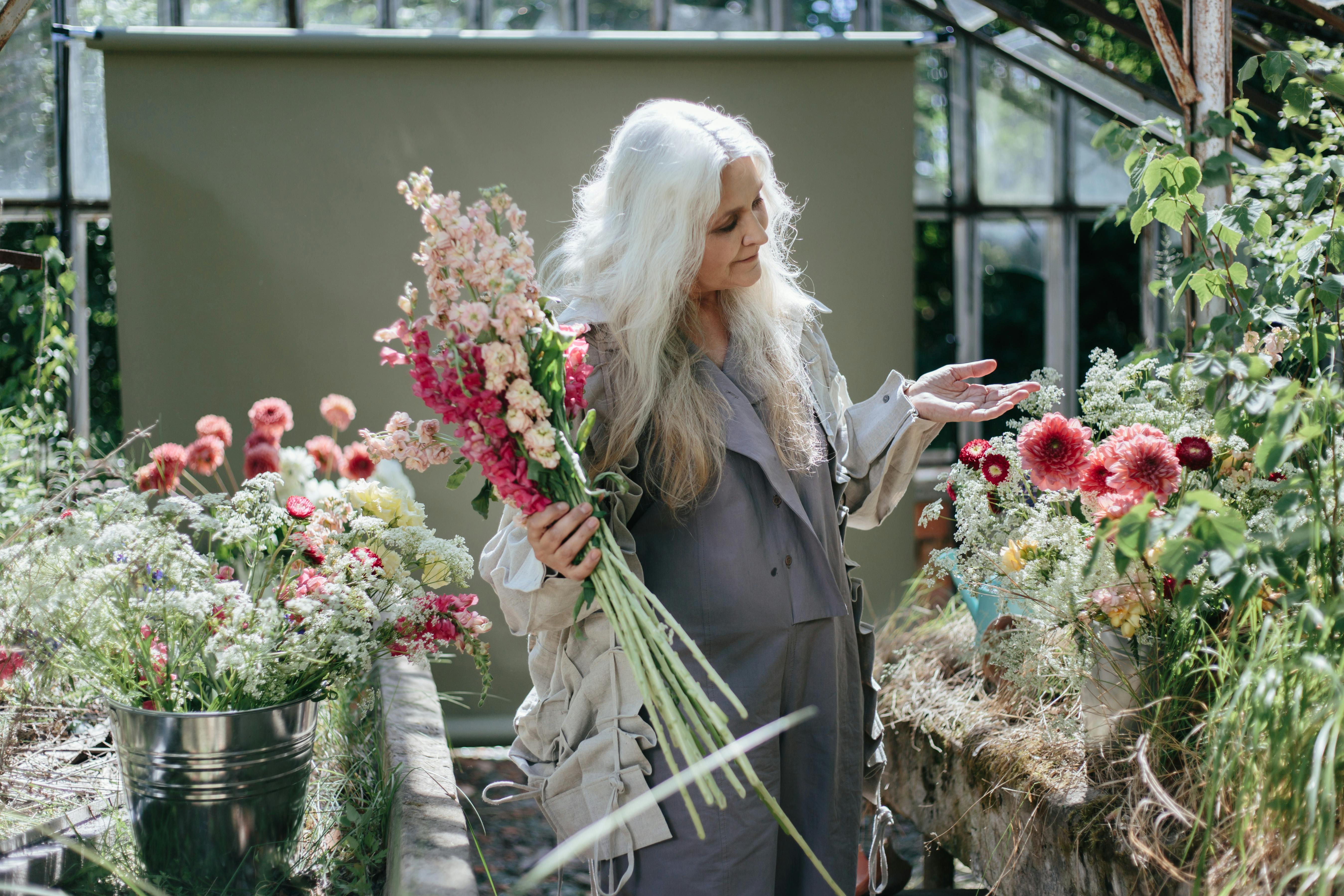 Uma senhora idosa rodeada de flores | Fonte: Pexels