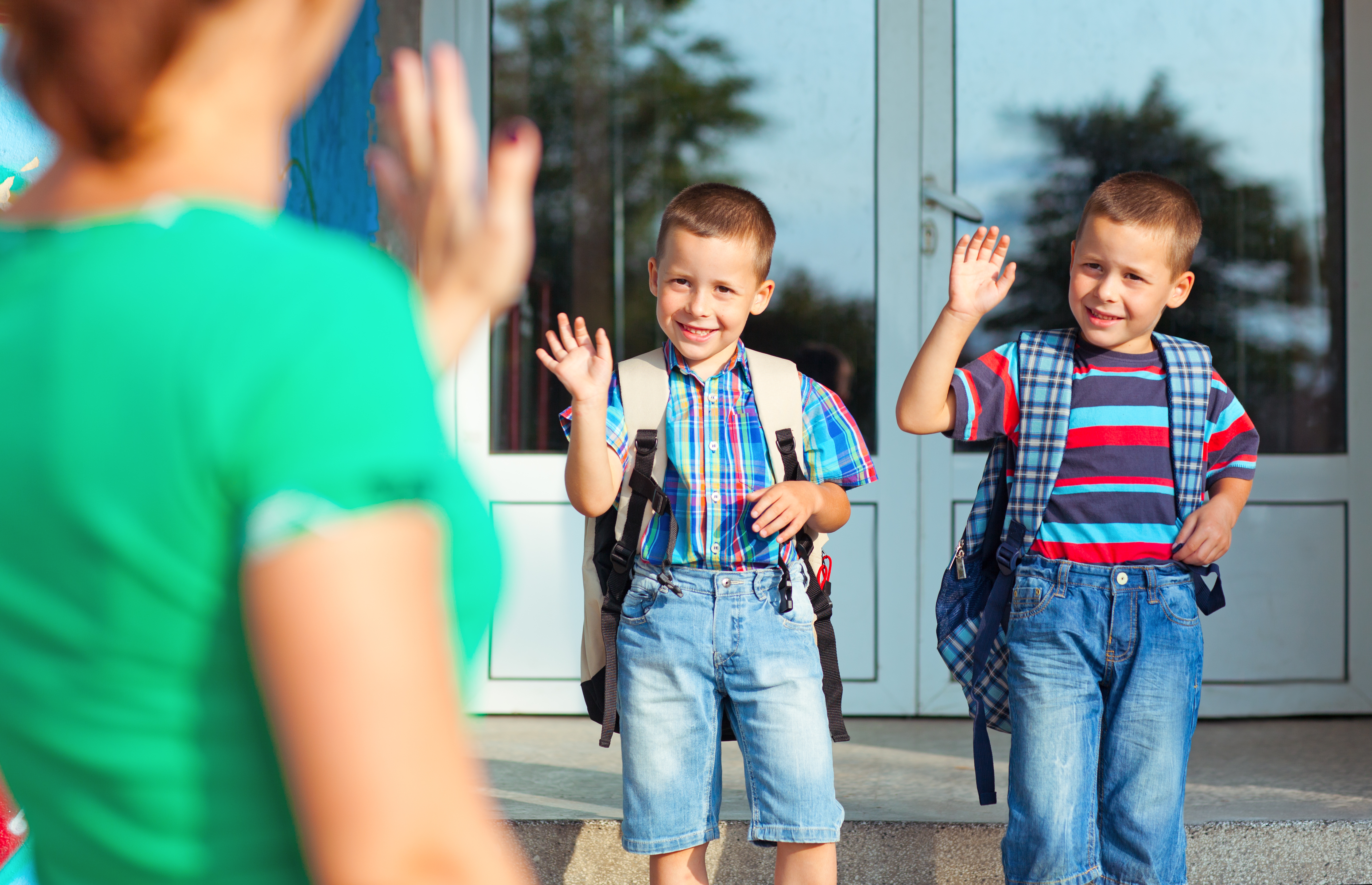 Uma mãe acenando para seus filhos gêmeos | Fonte: Shutterstock