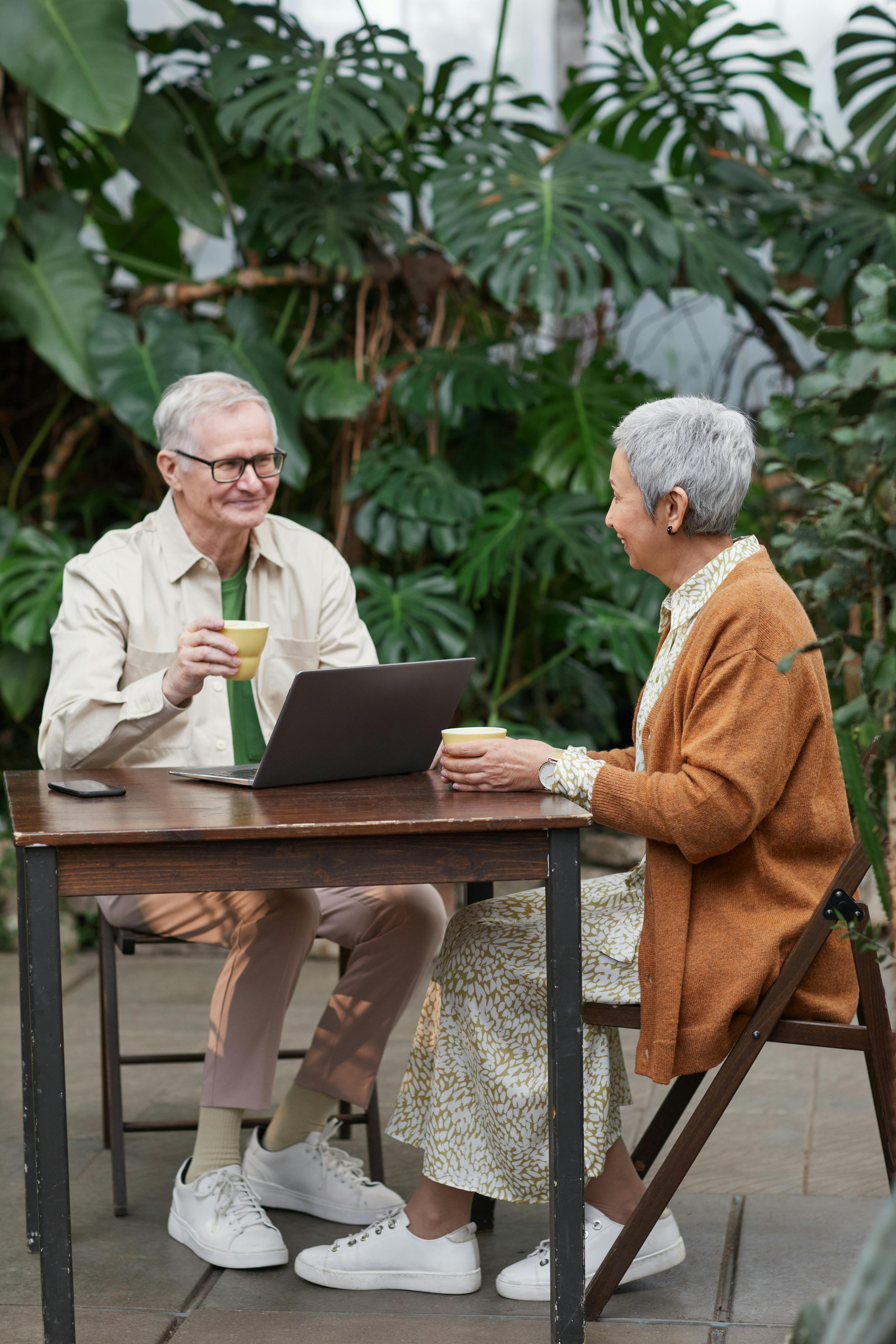 A couple flirting and smiling while enjoying beverages with a laptop visible | Source: Pexels