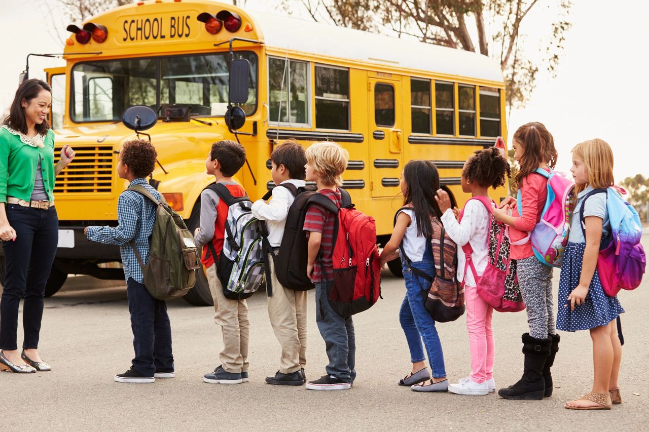 Elementary school students line up before a school bus. | Source: Shutterstock