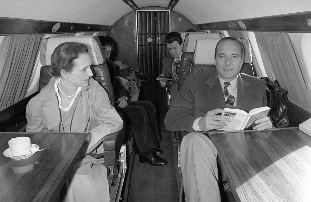 Jacques Chirac (D), accompagné de sa fille aînée Laurence (G) lit un livre le 26 avril 1981 dans l'avion qui l'emmène à Sarran où il doit voter pour le premier tour des élections. | Photo : Getty Images