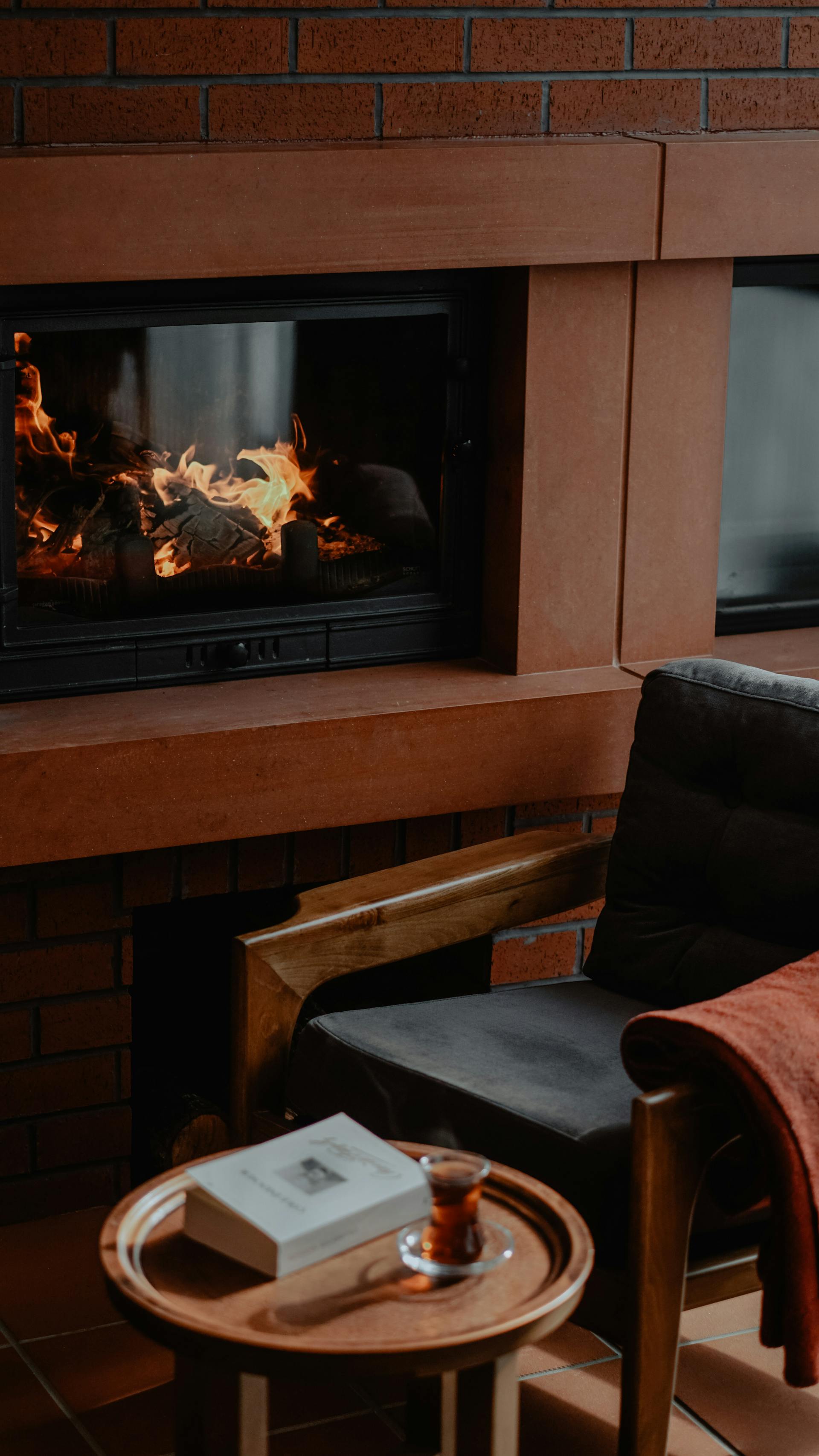 An armchair and a table next to an electric fireplace | Source: Pexels