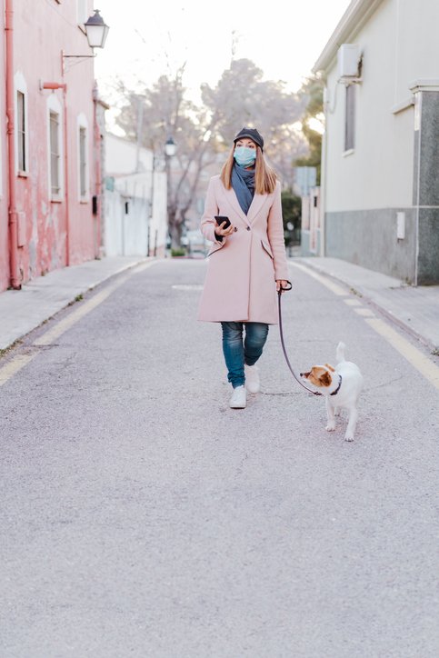 Mujer usando tapabocas y dando un paseo con su perro por las calles. | Foto: Getty Images
