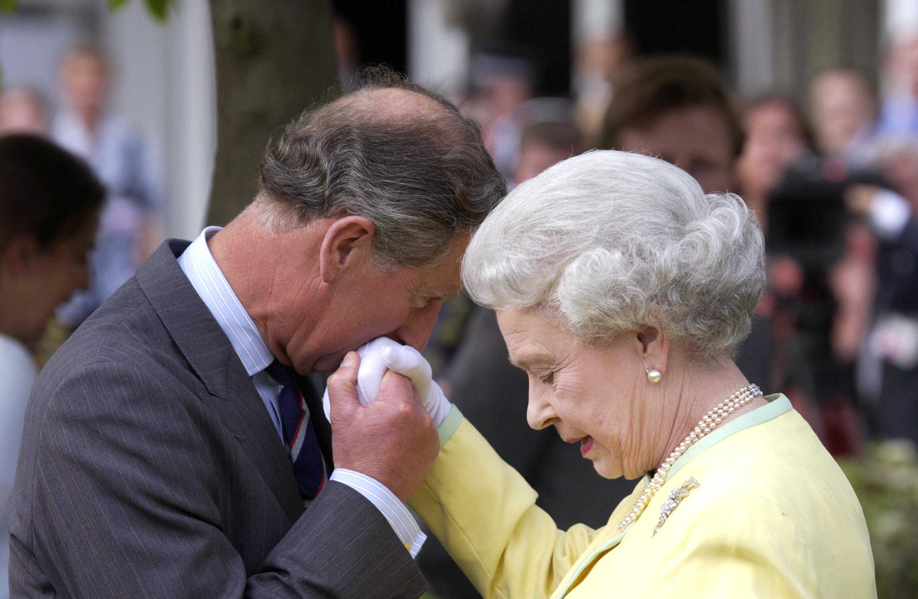 King Charles III, former Prince of Wales, kissing Queen Elizabeth II's hand at the Chelsea Flower Show in 2002 | Source: Getty Images