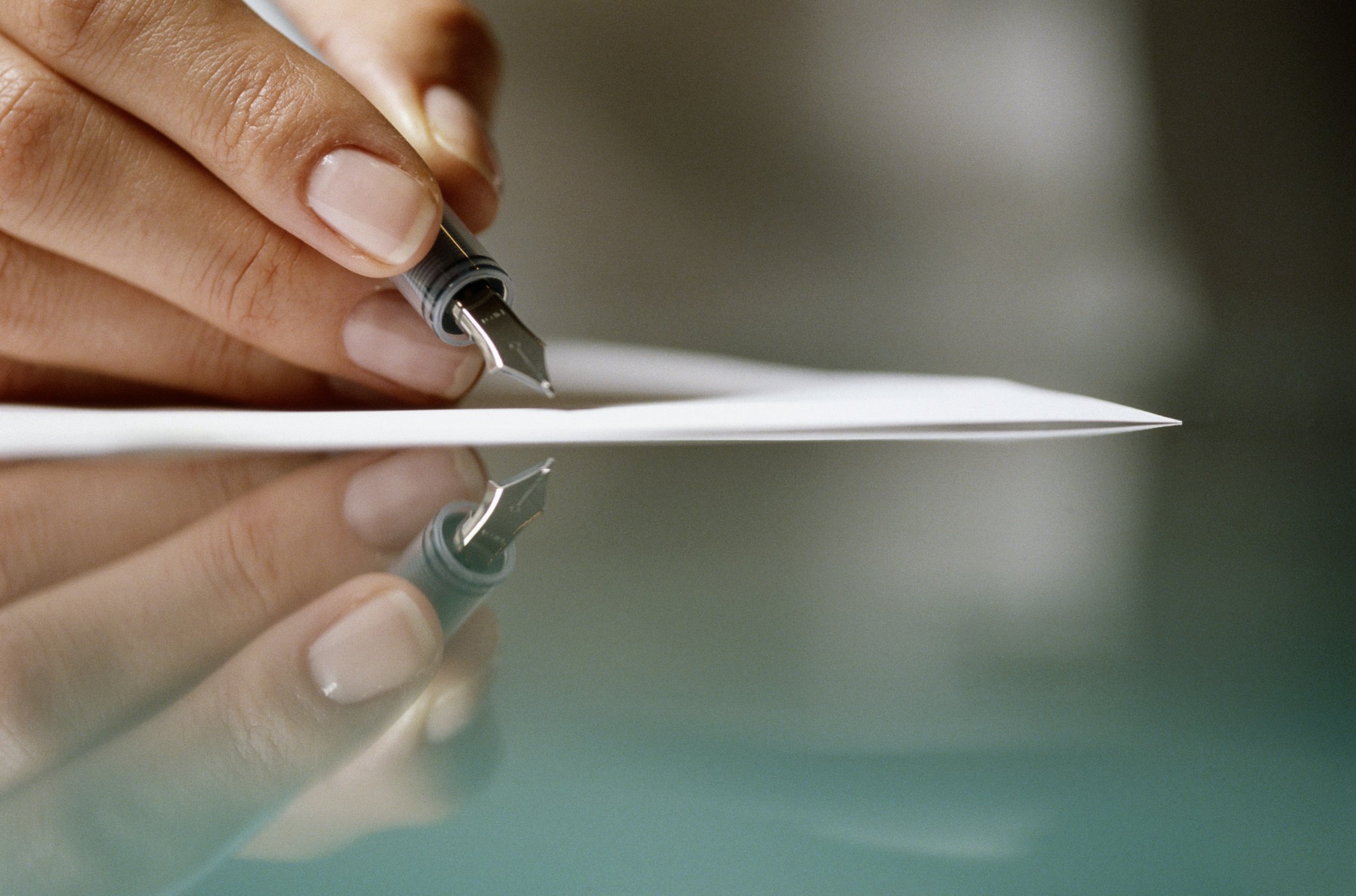 Frau, die auf Papier schreibt, und es wurde im Glastisch reflektiert | Quelle: Getty Images