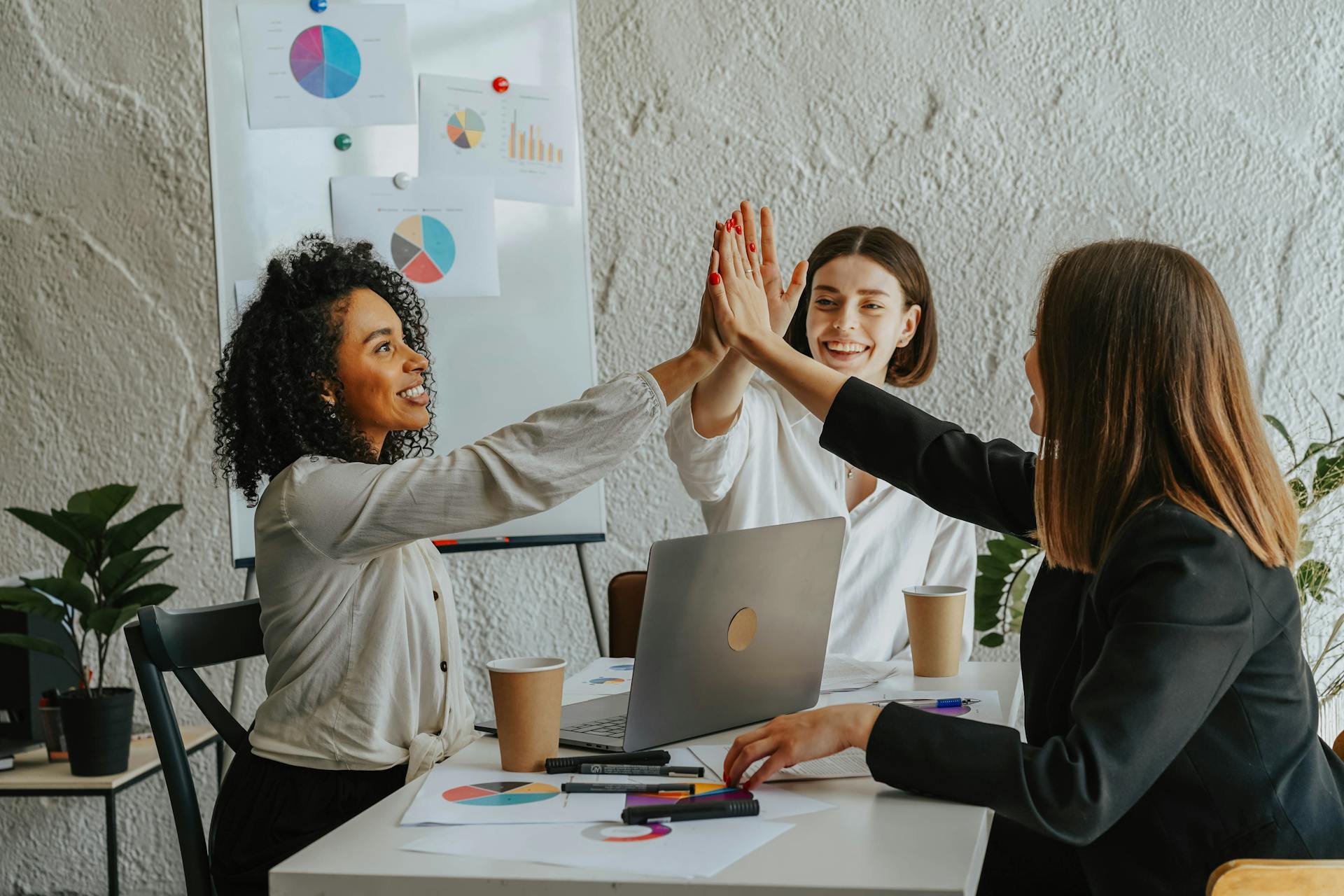 Women colleagues doing a high in the office | Source: Pexels