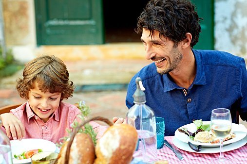 Happy father and son enjoying meal at outdoor table in yard | Photo: Getty Images
