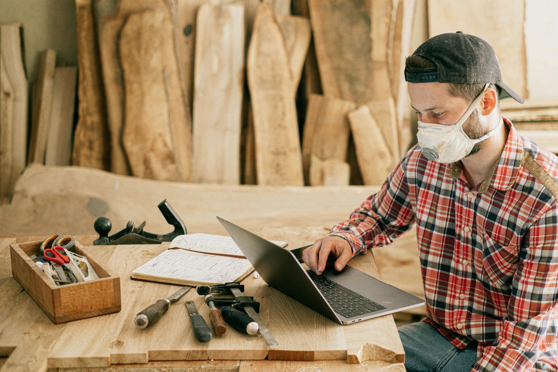 A man using a laptop in a wood workshop | Source: Pexels