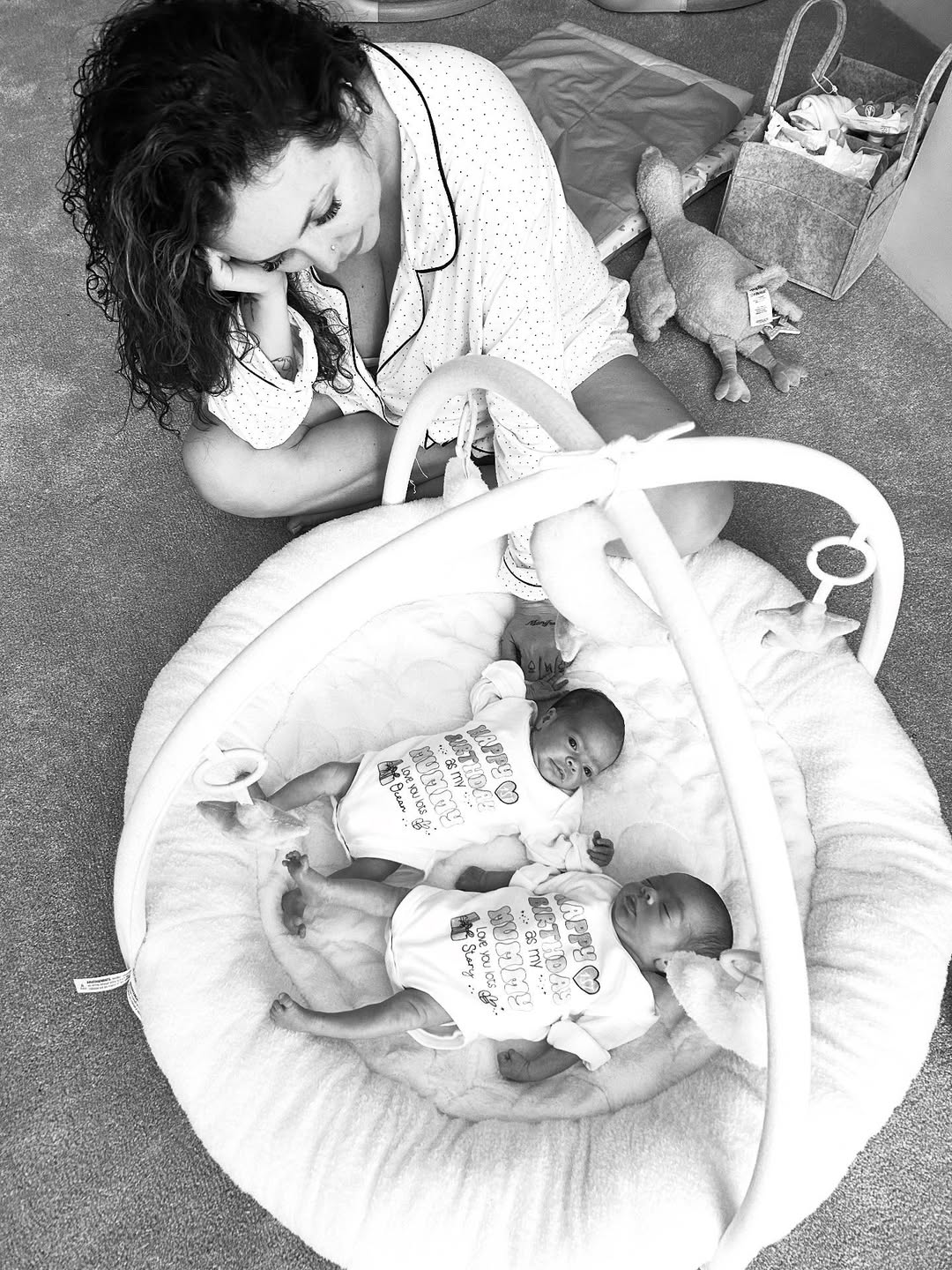 Nelson gazes tenderly at Ocean and Story, who lie side by side on a plush baby mat in matching outfits, surrounded by soft toys in a warm, quiet corner of home — a rare moment of peace for the devoted mum. | Source: Instagram/jesynelson