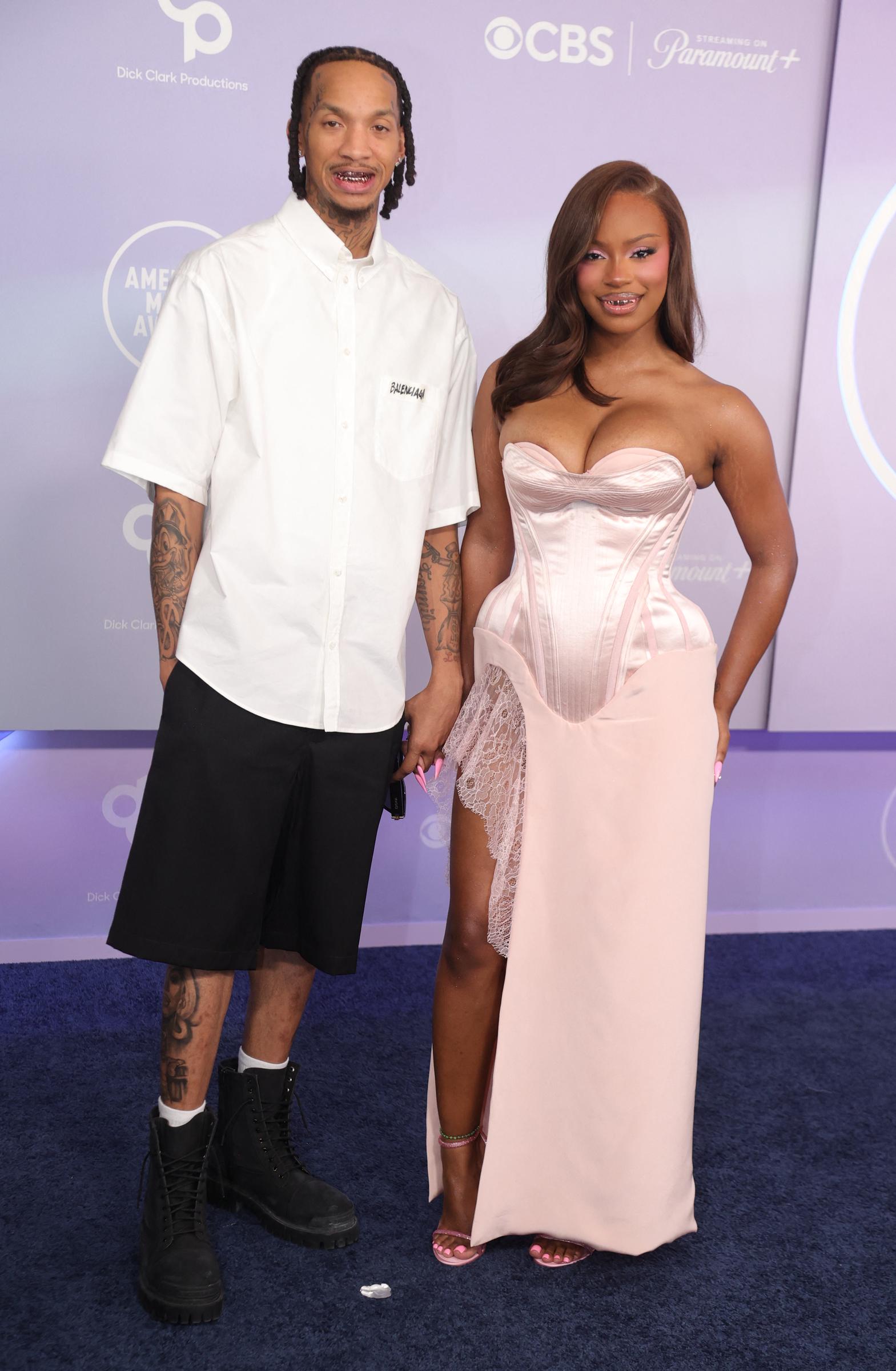 Stunna 4 Vegas kept things casual in an oversized white shirt and black shorts while standing beside Monaleo, who dazzled in a pale pink corset gown with dramatic structured detailing and lace accents. The pair balanced relaxed streetwear energy with ultra-glam femininity.