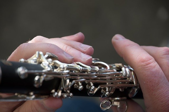 Close up photograph of the hands of a man playing a clarinet. I Image: Pixabay.