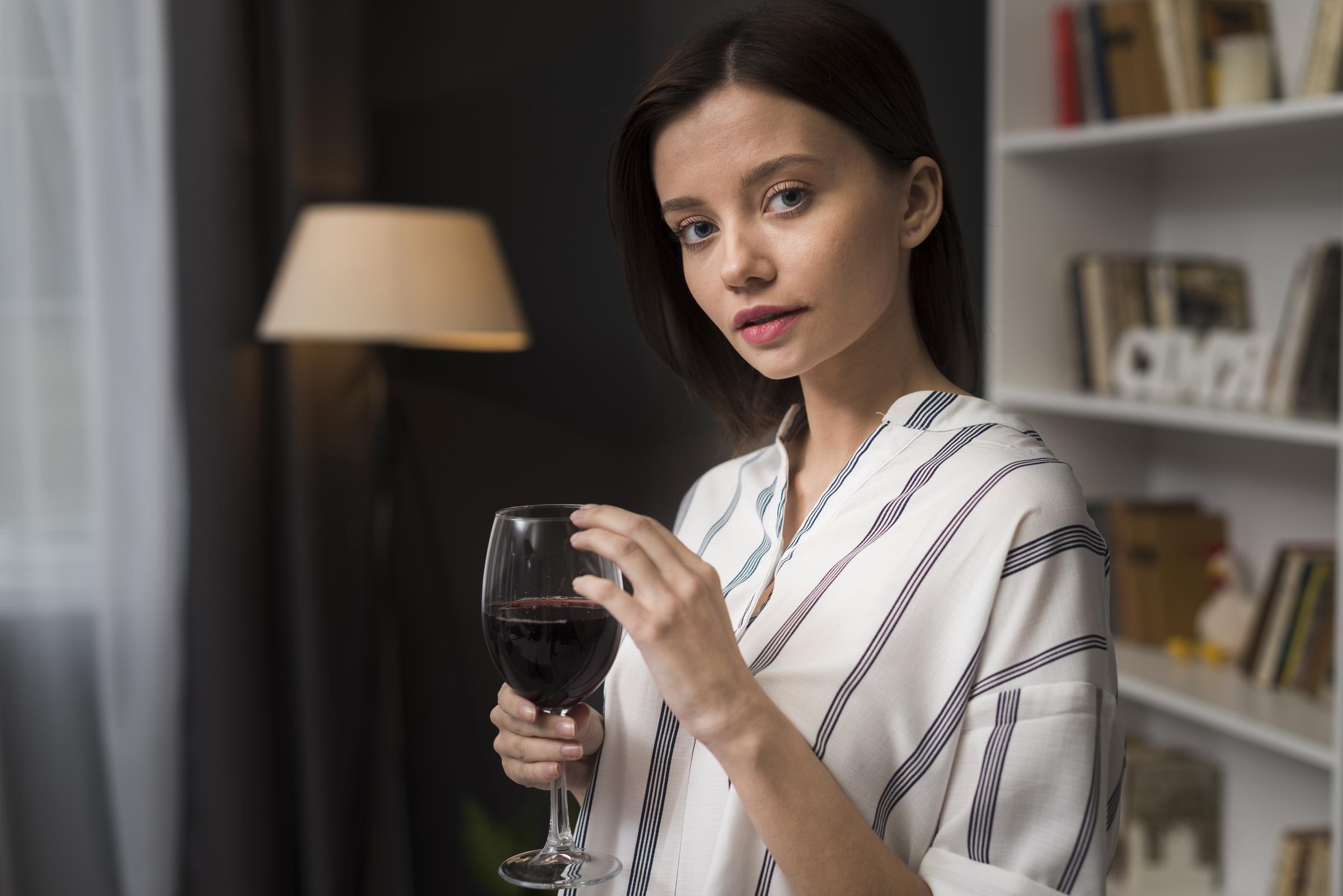 A woman holding a glass of wine | Source: Freepik