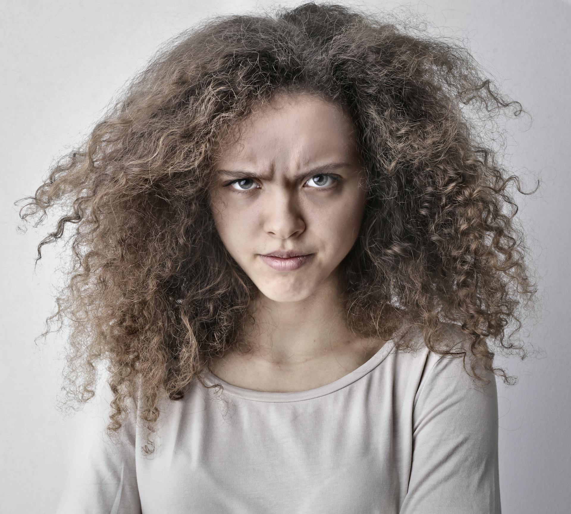 A young curly-haired woman furrowing her brows | Source: Pexels