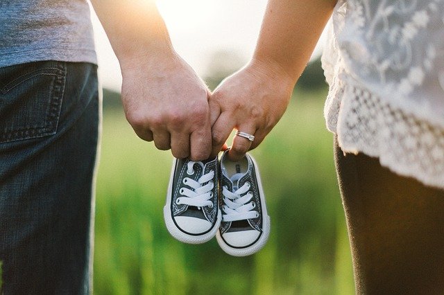 Couple walking together holding baby shoes | Source: Pixabay