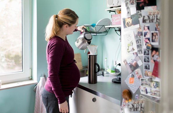 A pregnant woman pictured preparing coffee in her kitchen | Photo: Getty Images