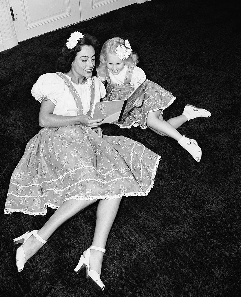 Joan Crawford reads a book to Christina, June 1944 | Photo: Getty Images