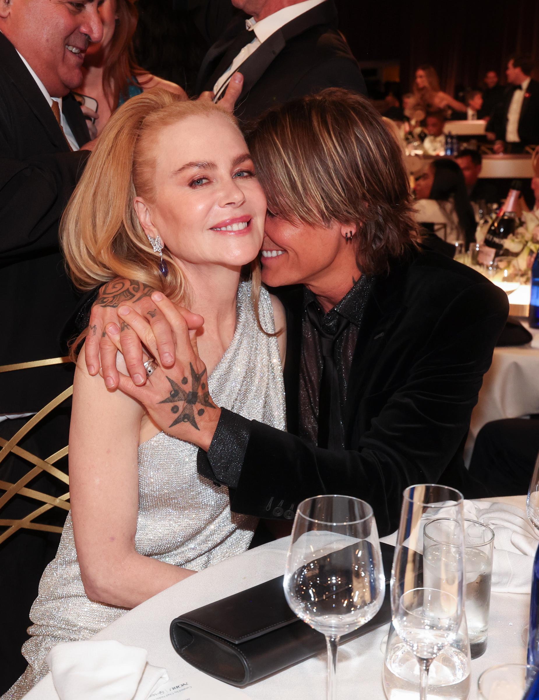Keith Urban pulls Nicole Kidman close in a snug embrace, his head gently tucked into her shoulder as the couple steals a rare moment of intimacy inside the buzzing awards ballroom.