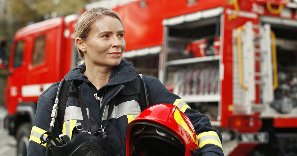A portrait of a young woman firefighter standing near a fire truck in Germany | Photo: Shutterstock/VAKS-Stock Agency
