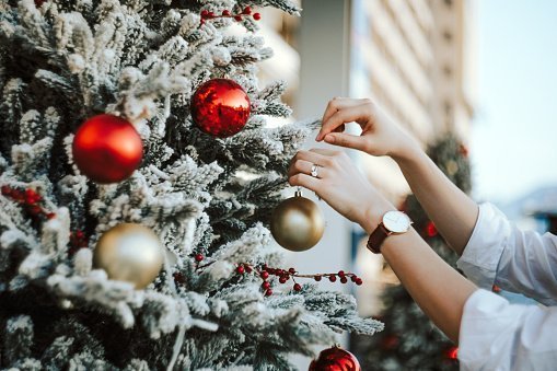 Woman decorating and hanging baubles on Christmas tree | Photo: Getty Images