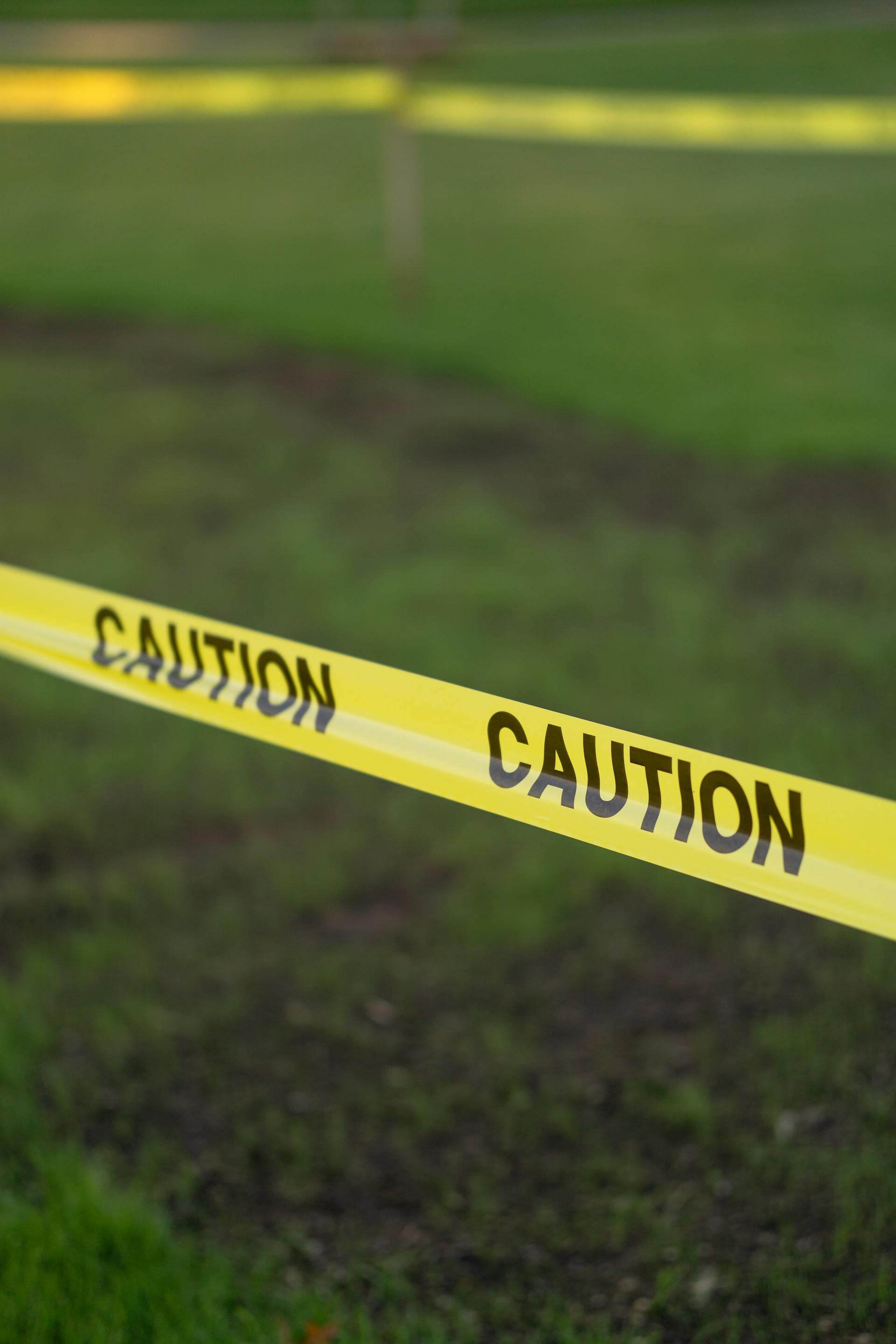 Close-up of a lawn secured with bright yellow caution tape | Source: Pexels