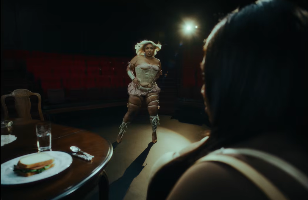 Lizzo strides forward under a spotlight, closing the distance between them | Source: YouTube/Lizzo
