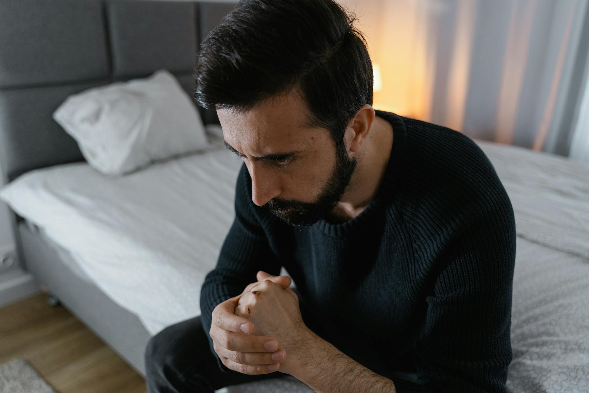 A man sitting on a bed looking angry | Source: Pexels