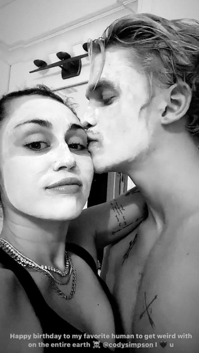 Miley Cyrus and Cody Simpson take a selfie with facial masks as her gives her a kiss on her forehead| Source: instagram.com/mileycyrus
