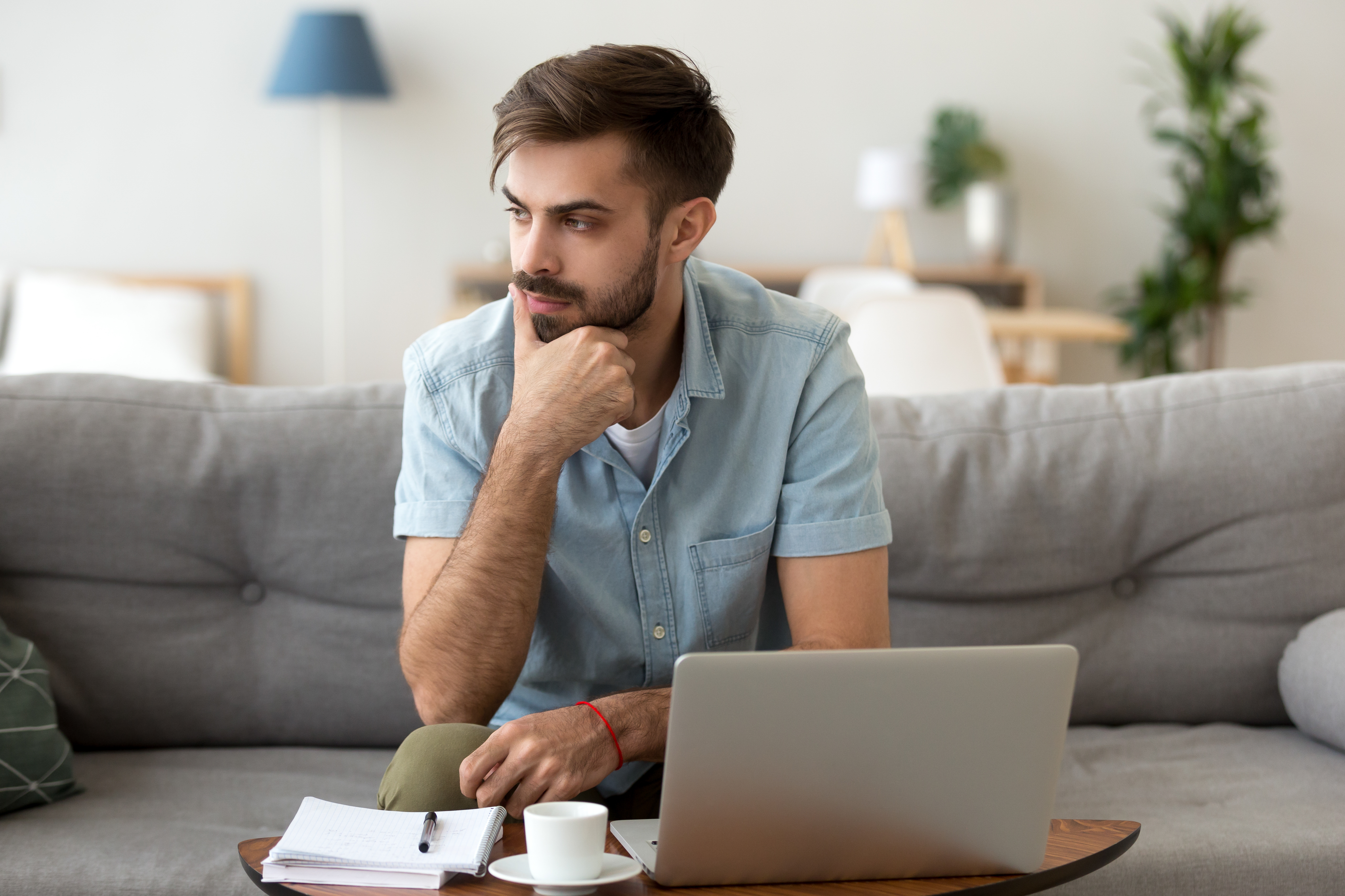 Young man sitting in front of a laptop looking concerned | Source: Shutterstock