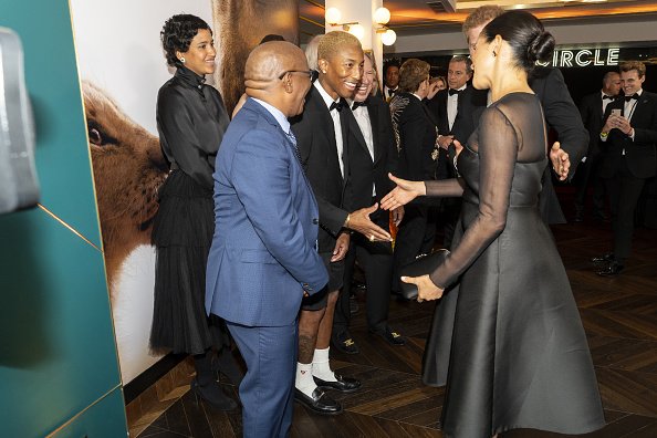 El príncipe Harry, duque de Sussex y Meghan, duquesa de Sussex saludan al cantante estadounidense Pharrell Williams en el estreno europeo de "The Lion King" de Disney en Odeon Luxe Leicester Square el 14 de julio de 2019 en Londres, Inglaterra. | Fuente: Getty Images