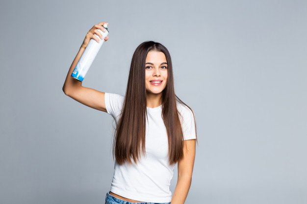 Mujer rociándose spray para el cabello. | Foto: Freepik Mujer rociándose spray para el cabello. | Foto: Freepik