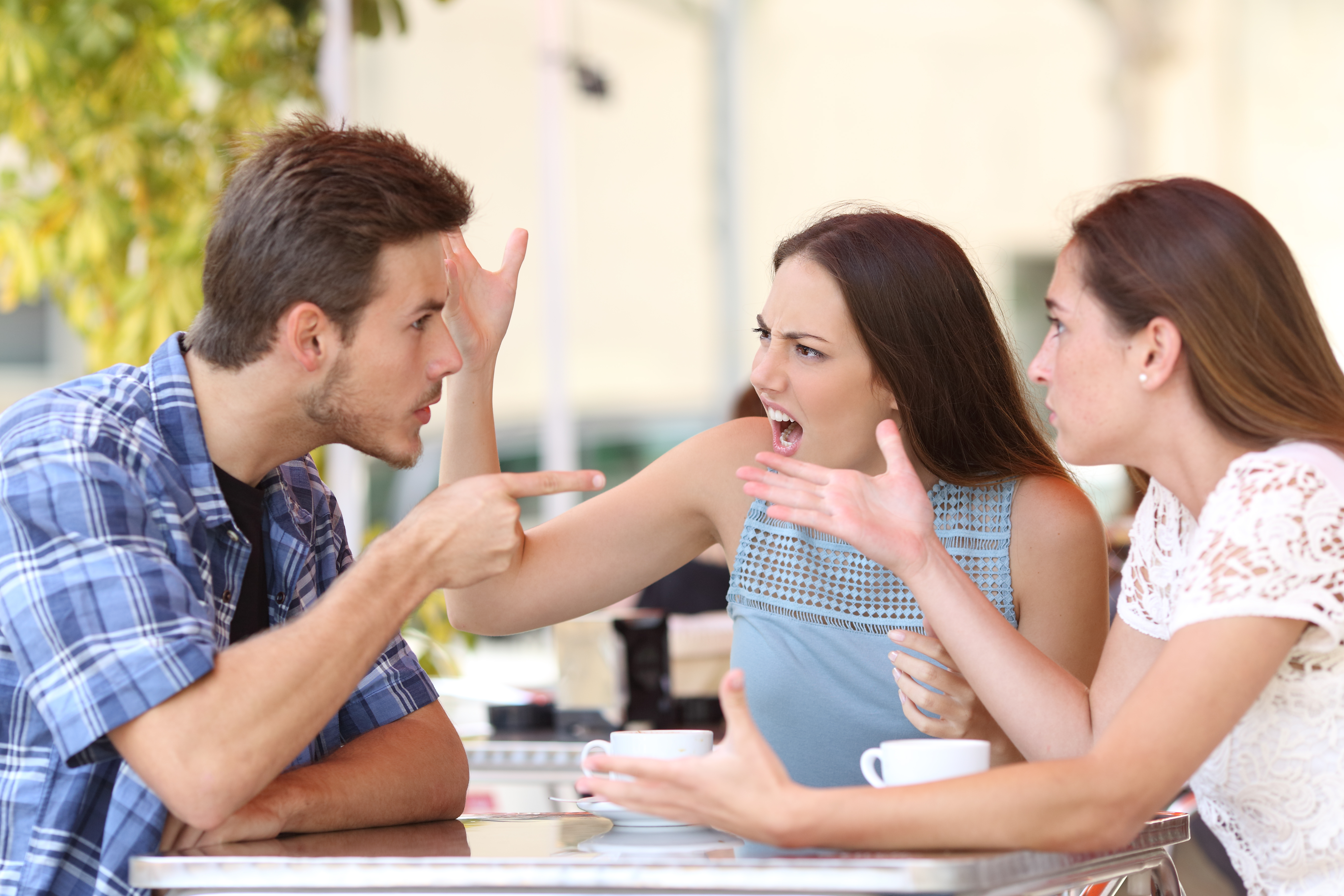 Two women and man arguing in public | Source: Shutterstck