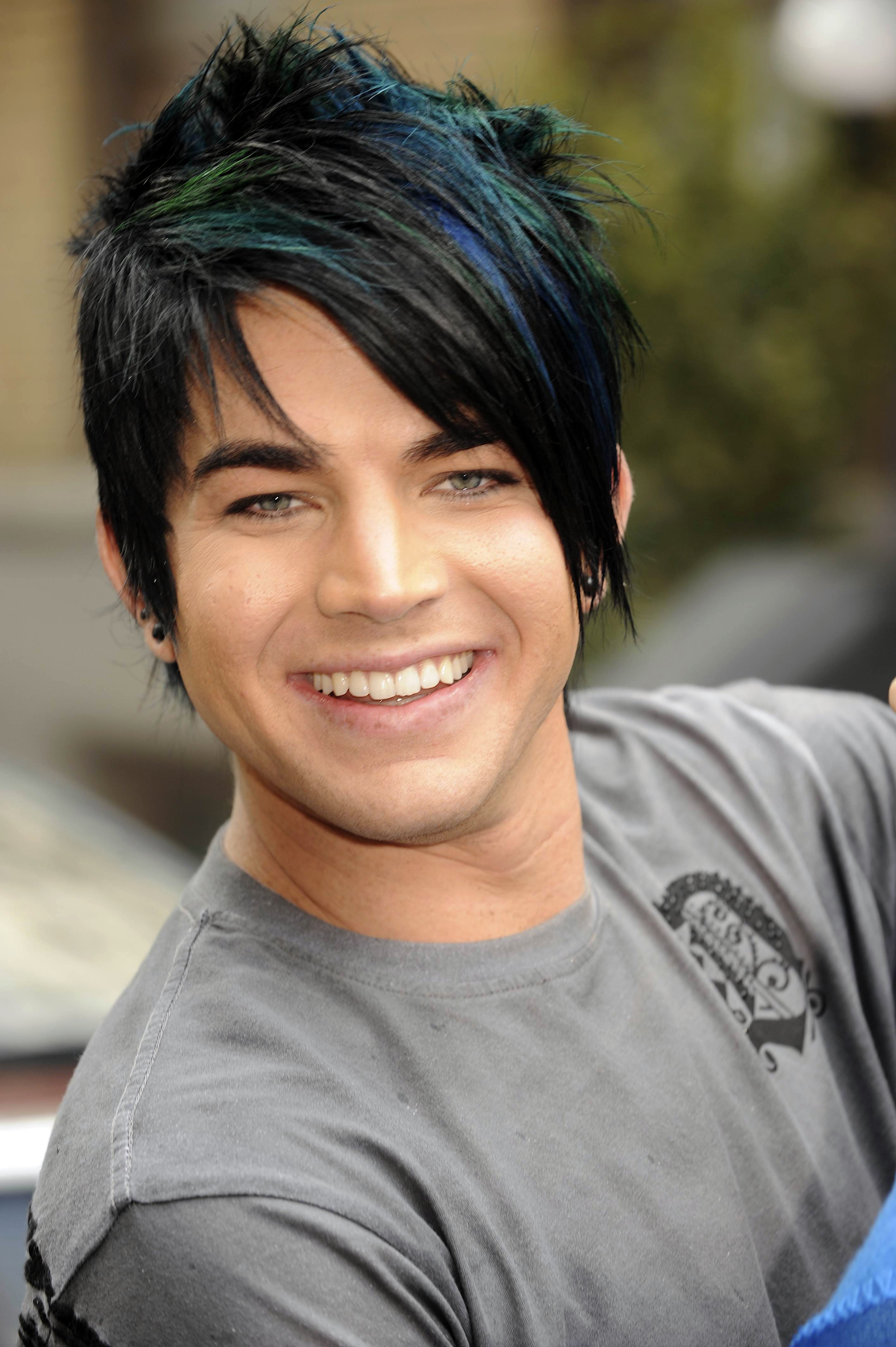 Smiling brightly in a grey tee, Adam Lambert poses during the making of a Ford American Idol music video in Los Angeles on March 15, 2009. His black hair, streaked with green and blue, hinted at the expressive style he would soon embrace more boldly.