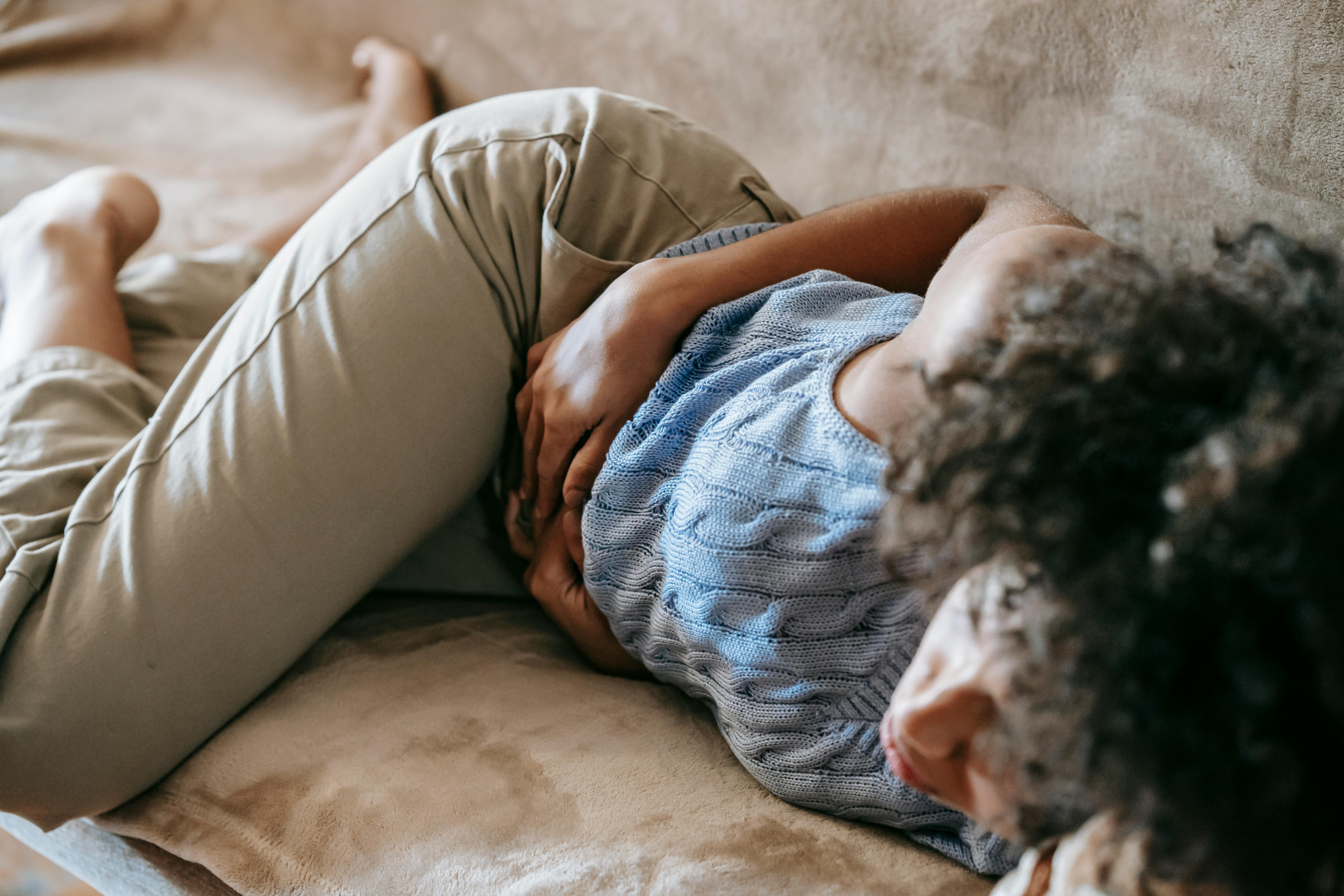 A woman holding her stomach in discomfort. | Source: Pexels