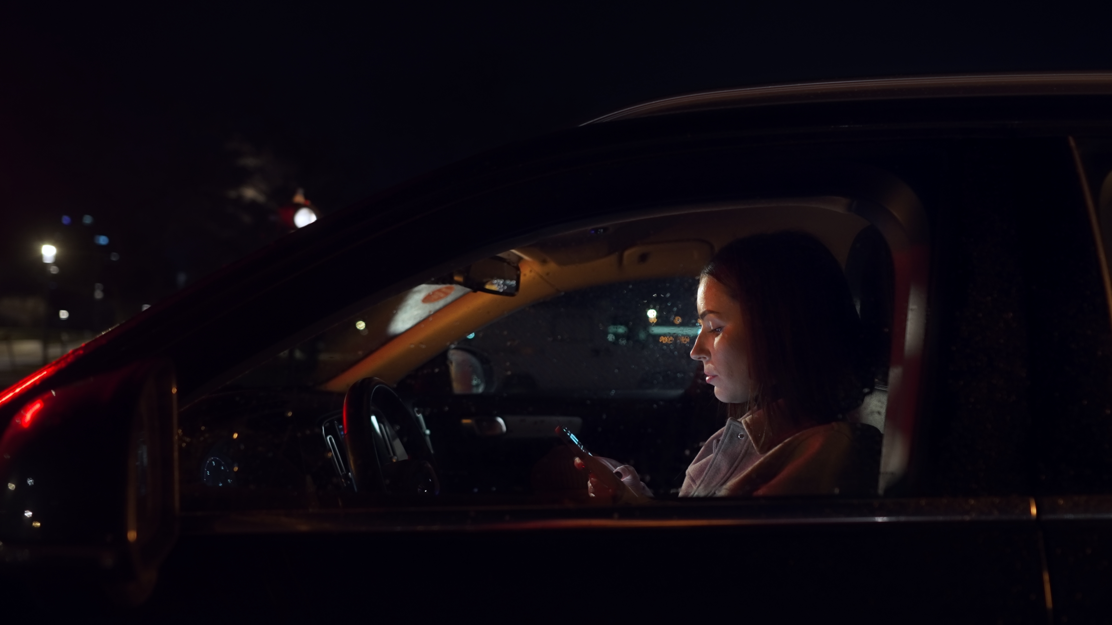 Woman using smartphone in a car at night. | Source: Shutterstock
