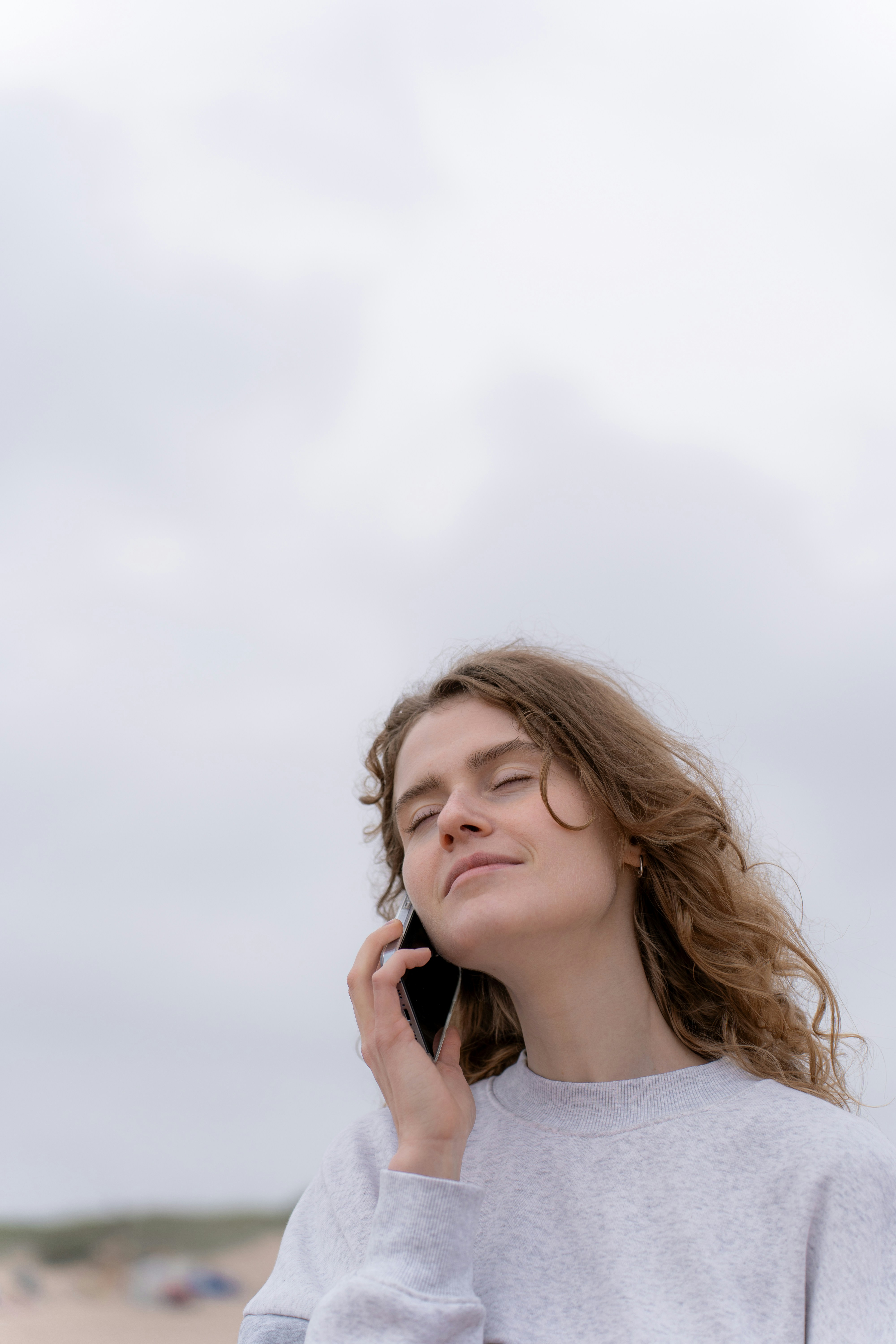 A woman with closed eyes talking on the phone | Source: Unsplash